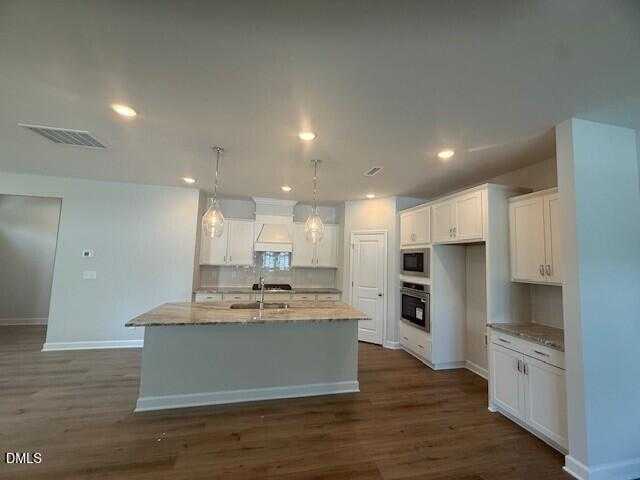 Spacious open-concept kitchen with white cabinets, granite island, stainless appliances in Davidson Homes Preston C, Lillington, NC