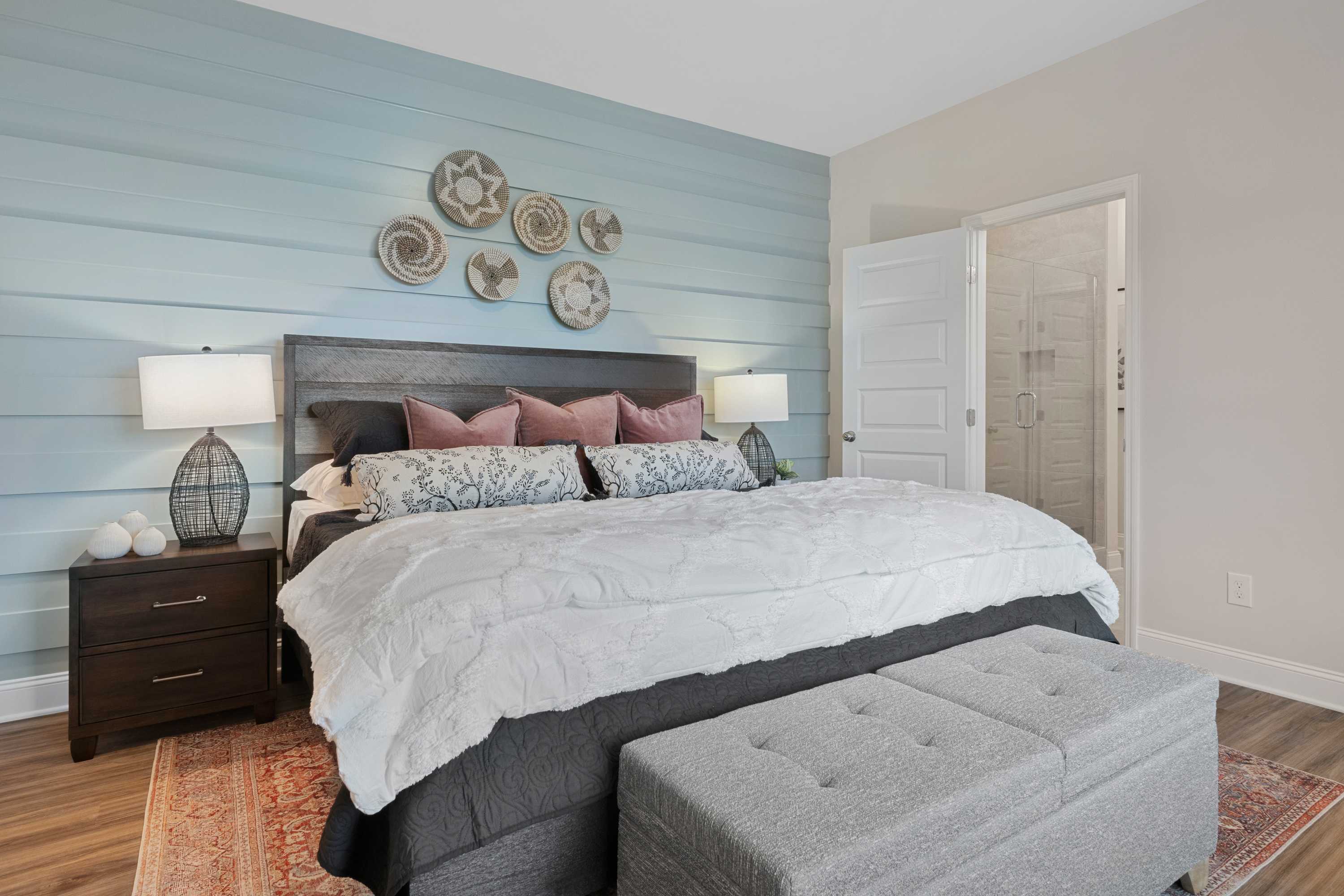 Cozy primary bedroom at The Retreat at Cain Park in Hartselle AL with shiplap walls, woven wall decor, king bed and en-suite bath