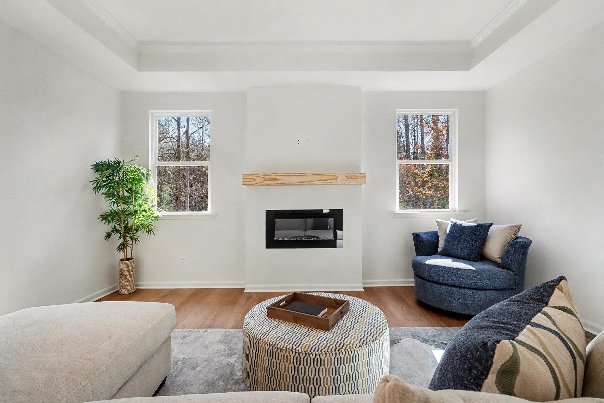Open-concept living room with shiplap gas fireplace, kitchen island sink, and wooded views in Davidson Homes The Daphne B, Loganville, GA