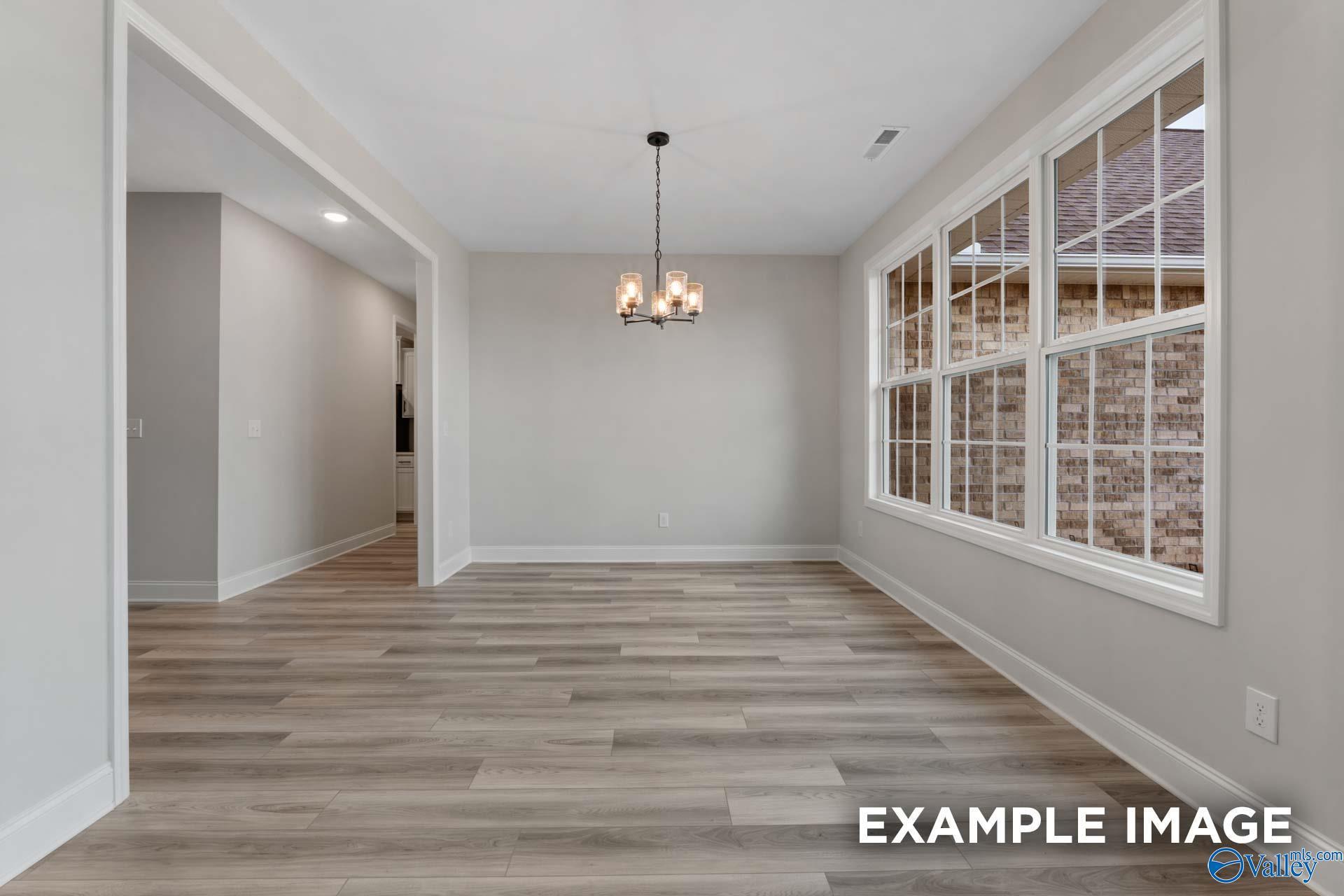 Bright dining room with chandelier, large windows, and gray walls in Davidson Homes The Finleigh, Meridianville, Alabama