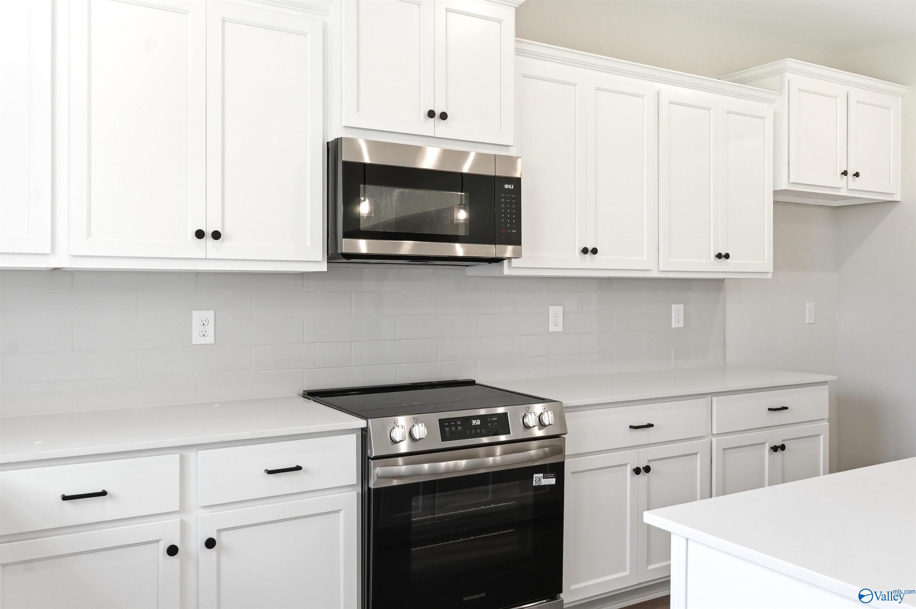 Modern kitchen with white cabinets, quartz countertops, and stainless steel appliances in The Chelsea D, Berry Cove home.