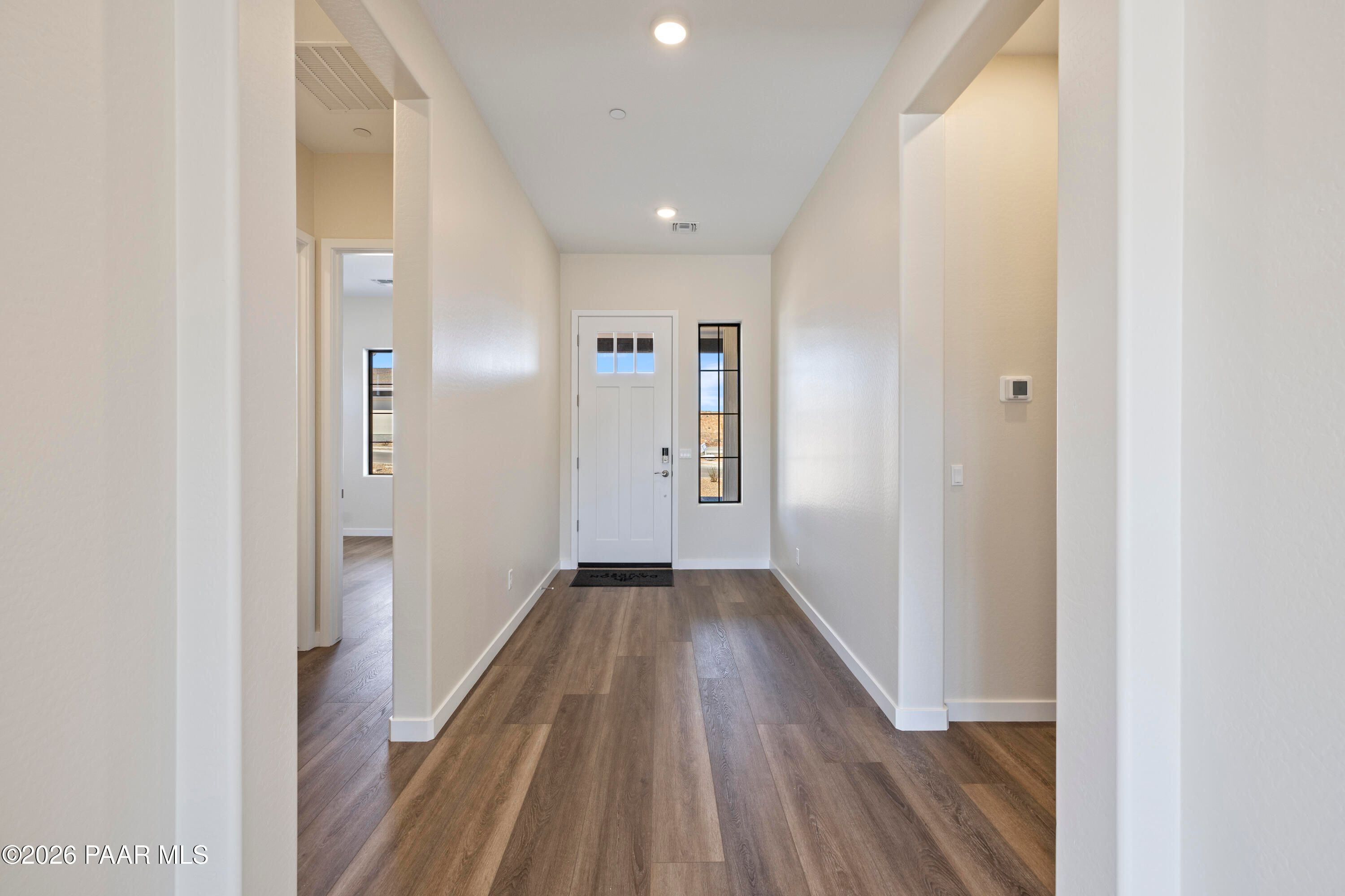 Bright entry hallway with luxury vinyl plank flooring, white walls, and sidelight door in Davidson Homes The Soleil E, Prescott AZ