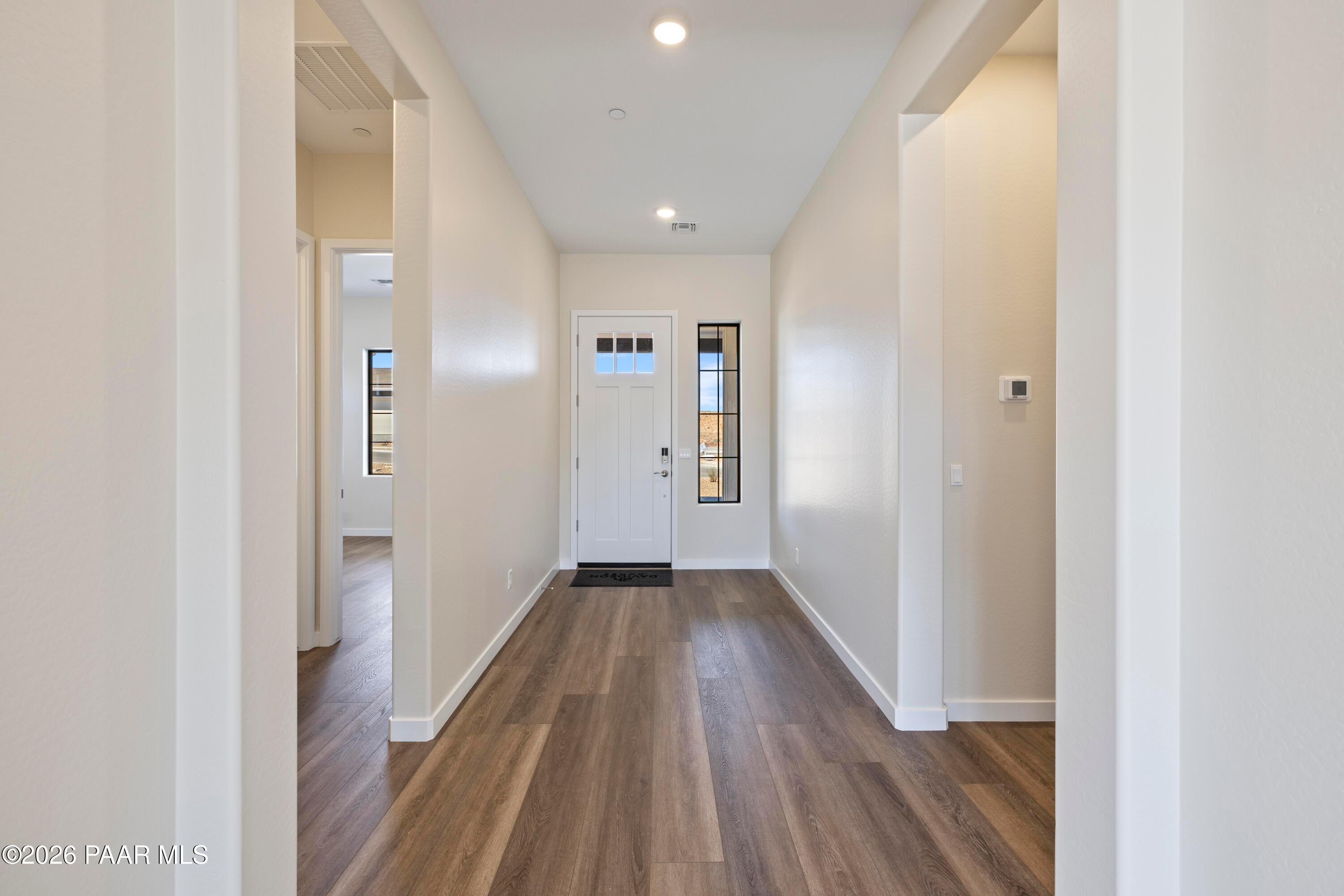 Bright entry hallway with luxury vinyl plank flooring, white walls, and sidelight door in Davidson Homes The Soleil E, Prescott AZ