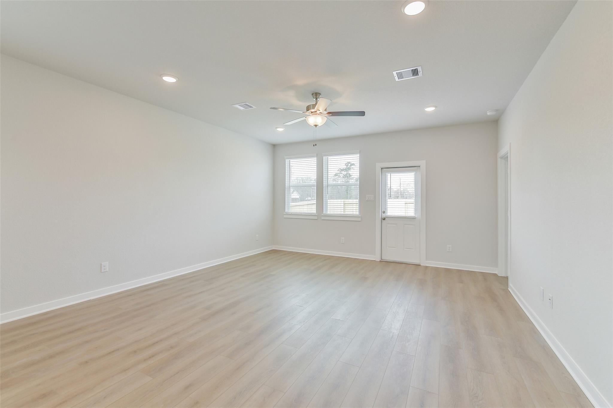 Bright living room with ceiling fan, recessed lights, hardwood floors, large windows in The Brazos E home, Cleveland, Texas