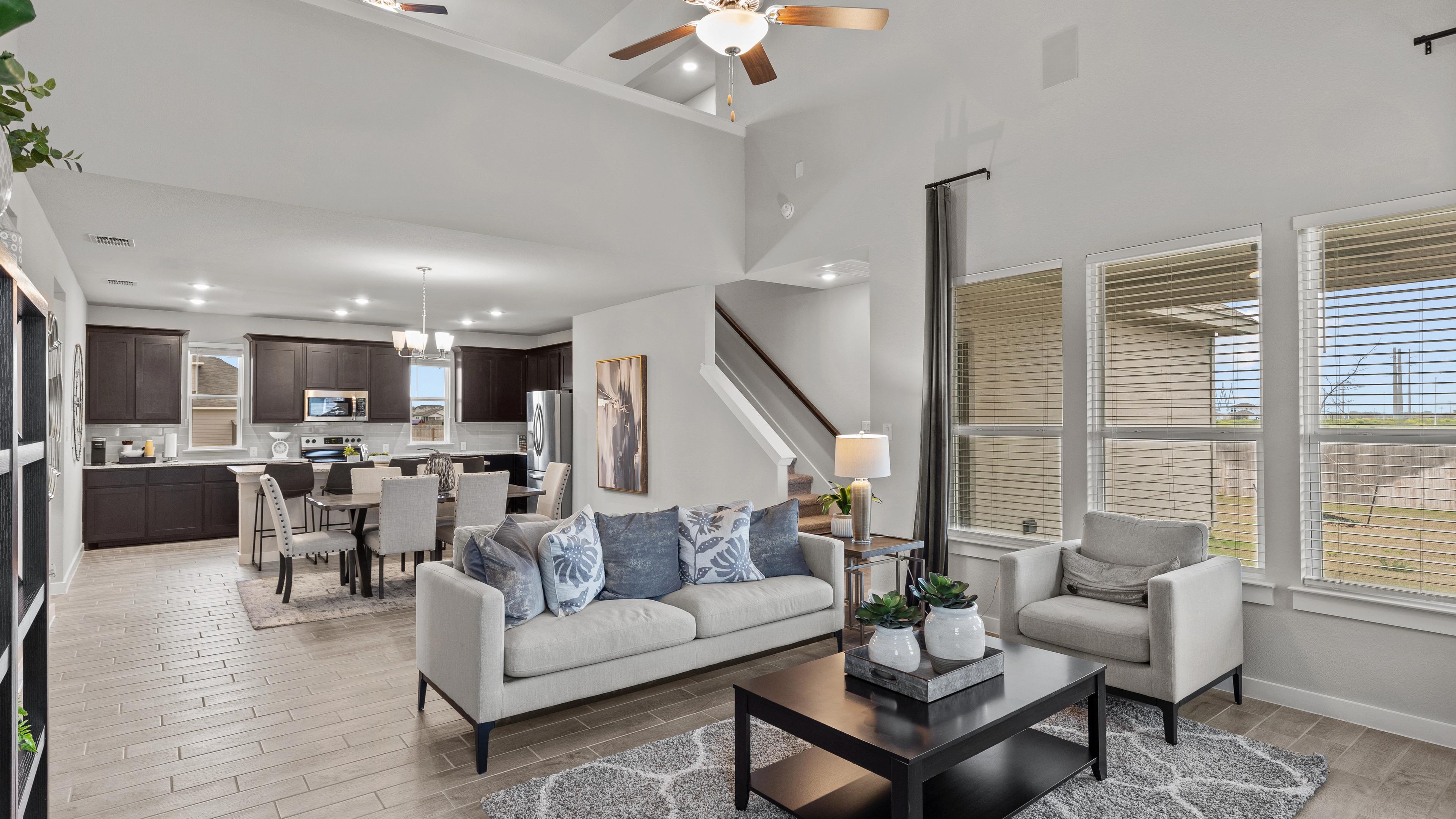 Open-concept living kitchen dining area at Hannah Heights in Seguin Texas with gray sofa dark cabinets hardwood floors large windows