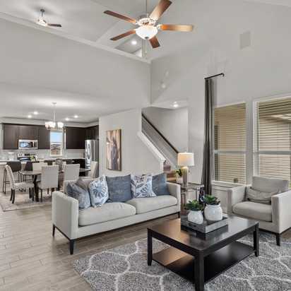Open-concept living kitchen dining area at Hannah Heights in Seguin Texas with gray sofa dark cabinets hardwood floors large windows