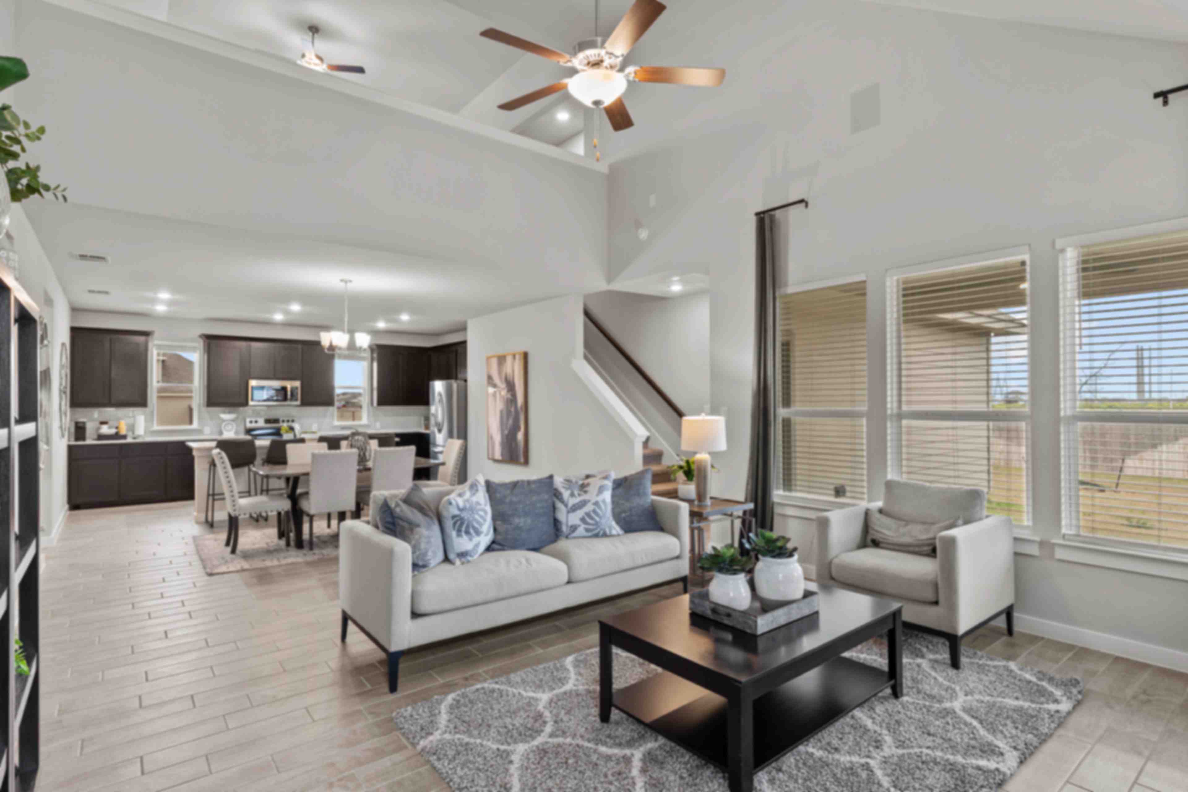 Open-concept living kitchen dining area at Hannah Heights in Seguin Texas with gray sofa dark cabinets hardwood floors large windows