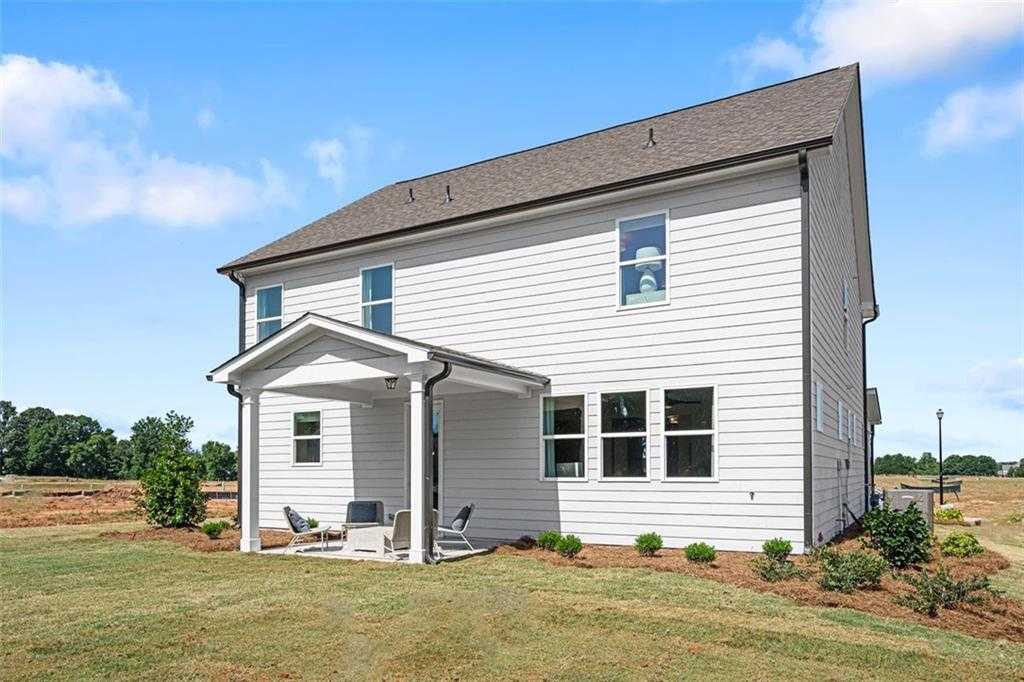 Rear view of Davidson Homes The Hickory C two-story with covered porch, outdoor seating, and lush lawn in Wehunt Meadows, Hoschton, Georgia