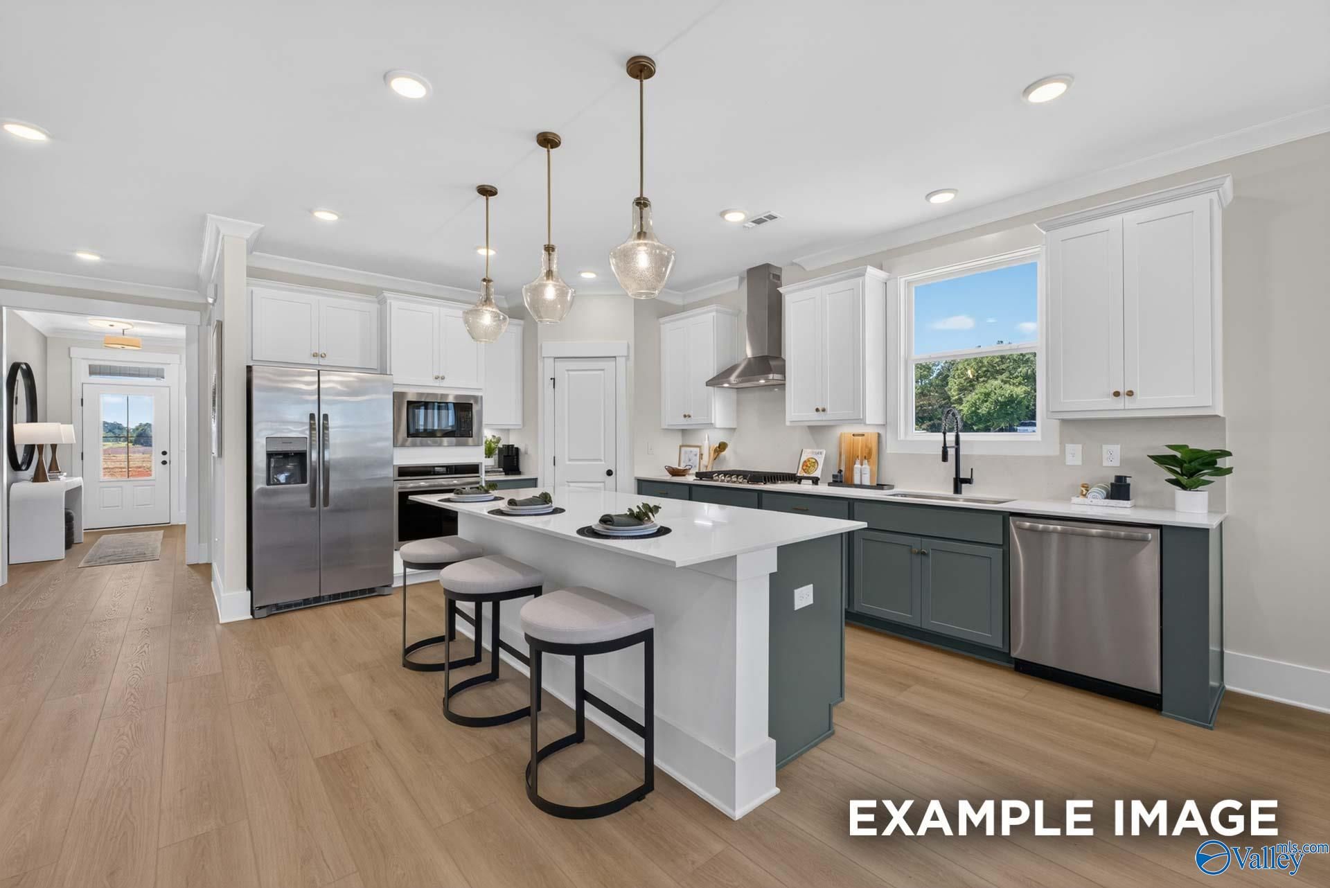 Modern kitchen with white island, gray cabinetry, stainless appliances, and pendant lights in The Ashport K, Forest Glen, Hazel Green, Alabama