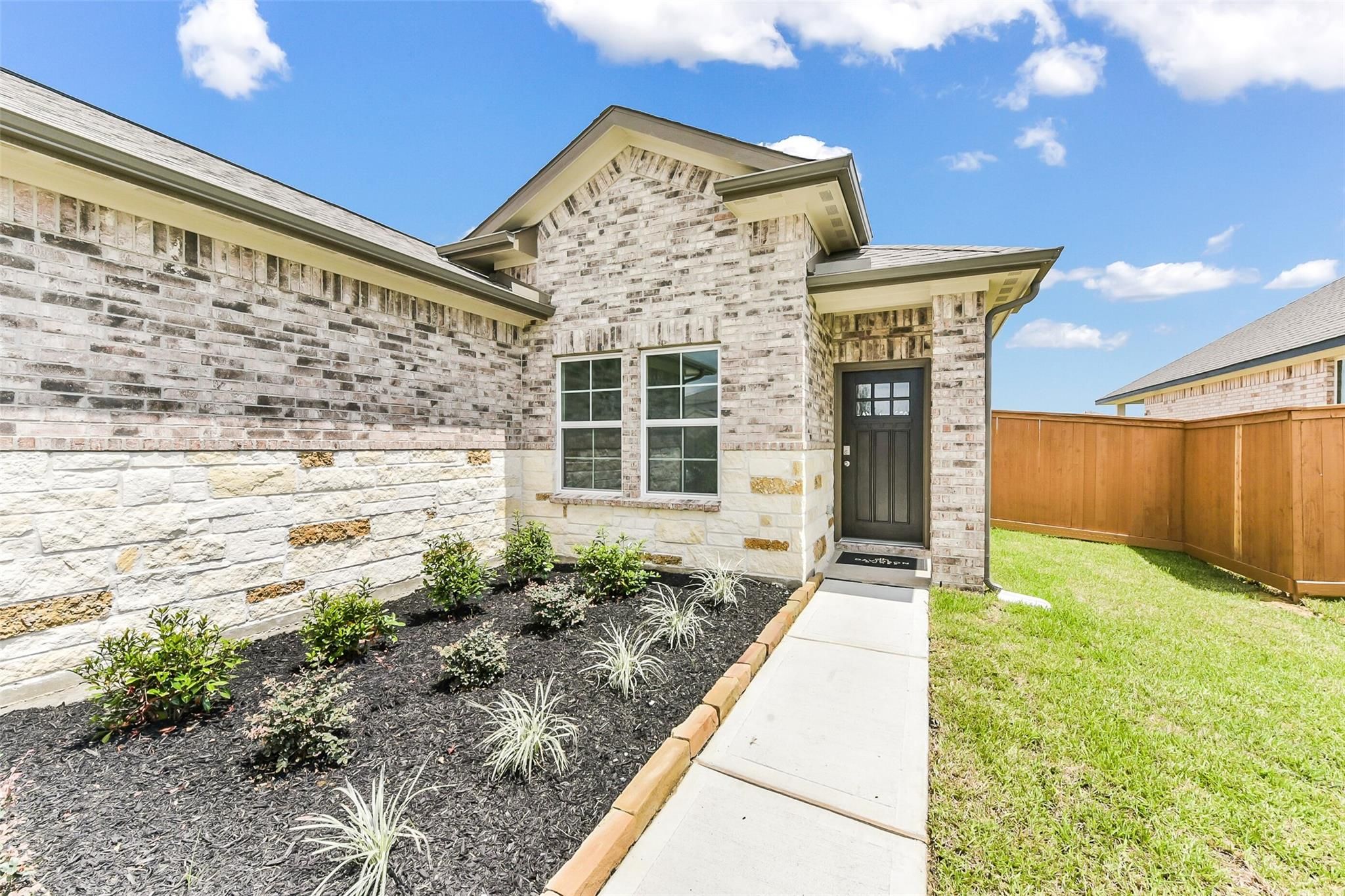 Modern brick and stone facade of The Costa B 3-car garage home by Davidson Homes in River Ranch Meadows, Dayton, Texas