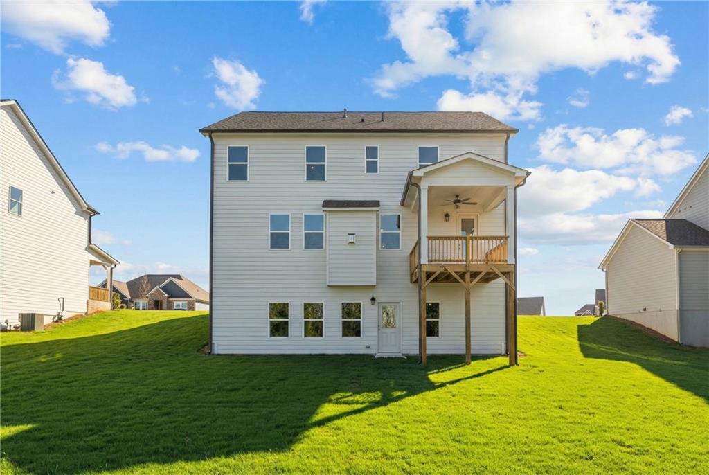 Rear view of 3-story white Davidson Homes residence with covered deck, balcony, and green yard in Wehunt Meadows, Hoschton, GA