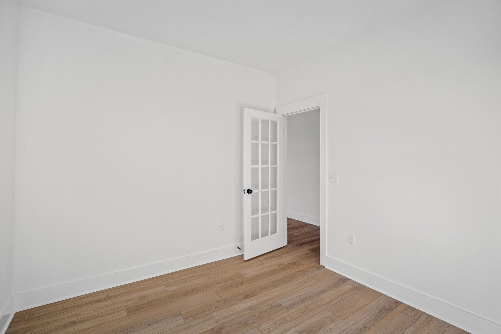 Bright empty bedroom with white walls, hardwood floors, and open glass-paneled door in The Willow floor plan, Gallatin, Tennessee