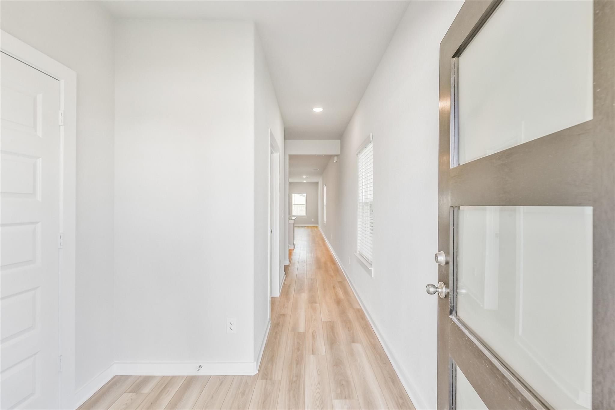 Bright entry hallway with hardwood floors, white walls, and modern doors in Davidson Homes The Rio Grande H, Magnolia, Texas