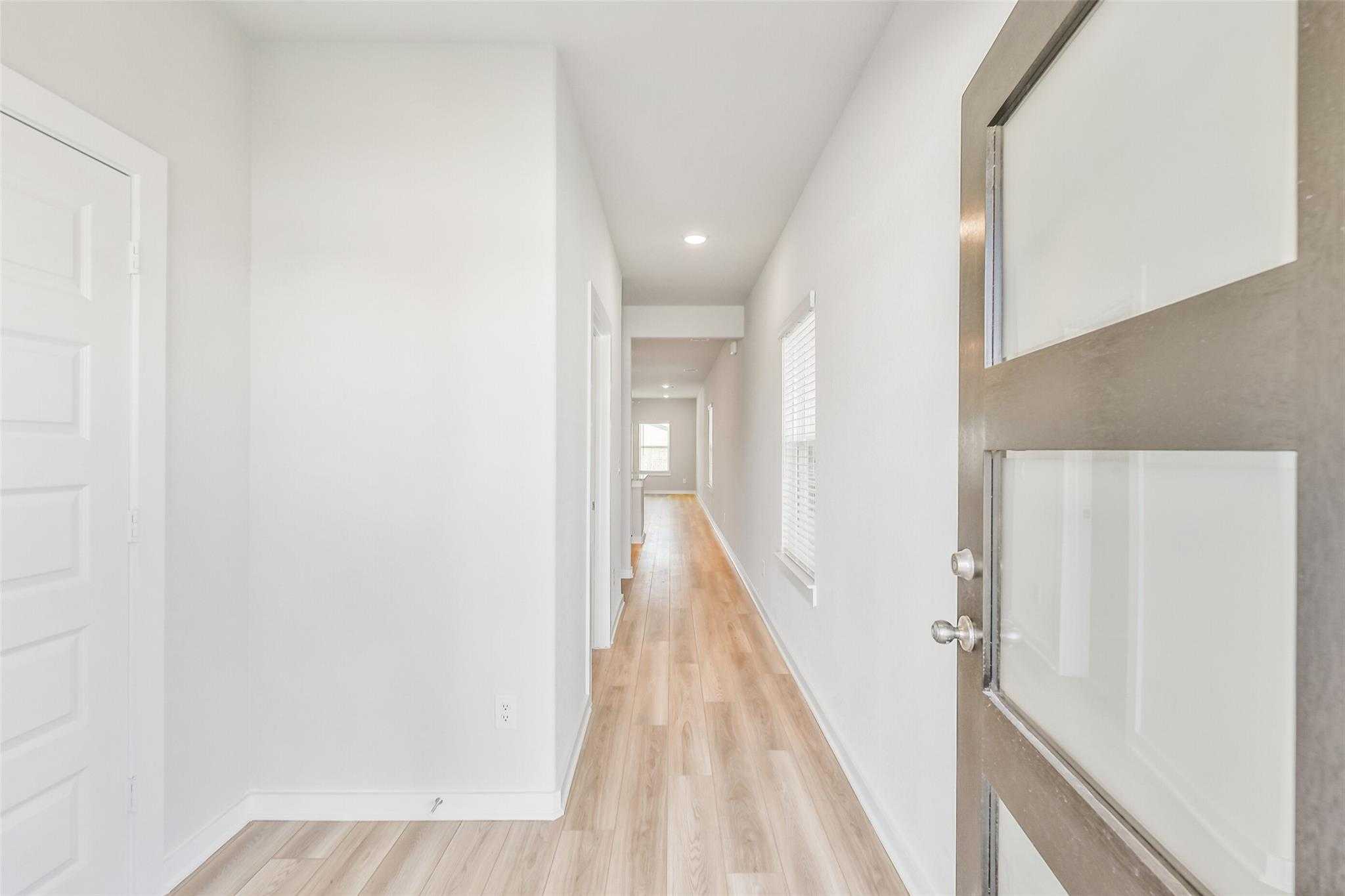 Bright entry hallway with hardwood floors, white walls, and modern doors in Davidson Homes The Rio Grande H, Magnolia, Texas