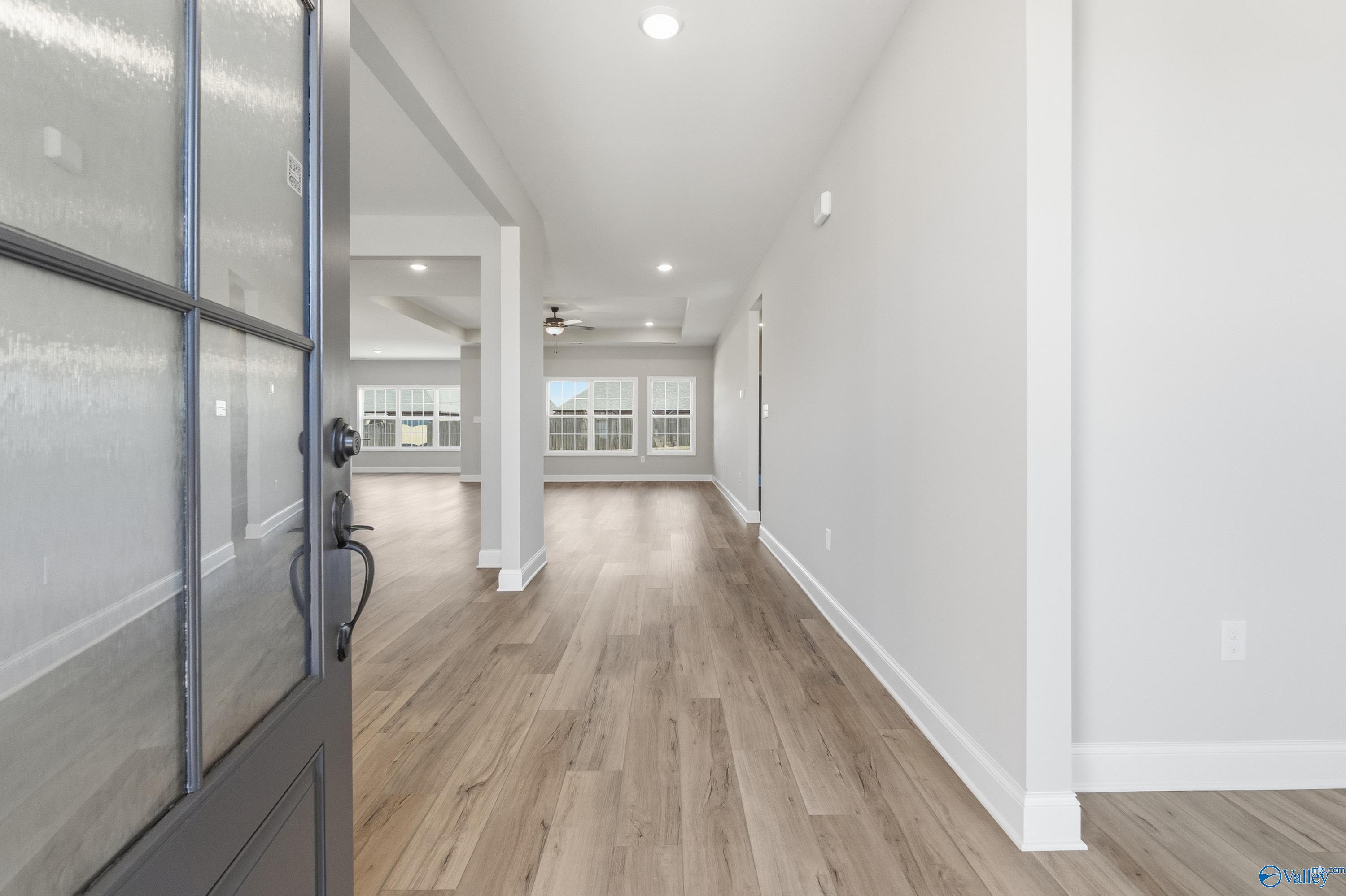 Inviting entry foyer with glass-paneled black door, light hardwood floors, and open hallway in Davidson Homes The Finleigh, Meridianville, Alabama