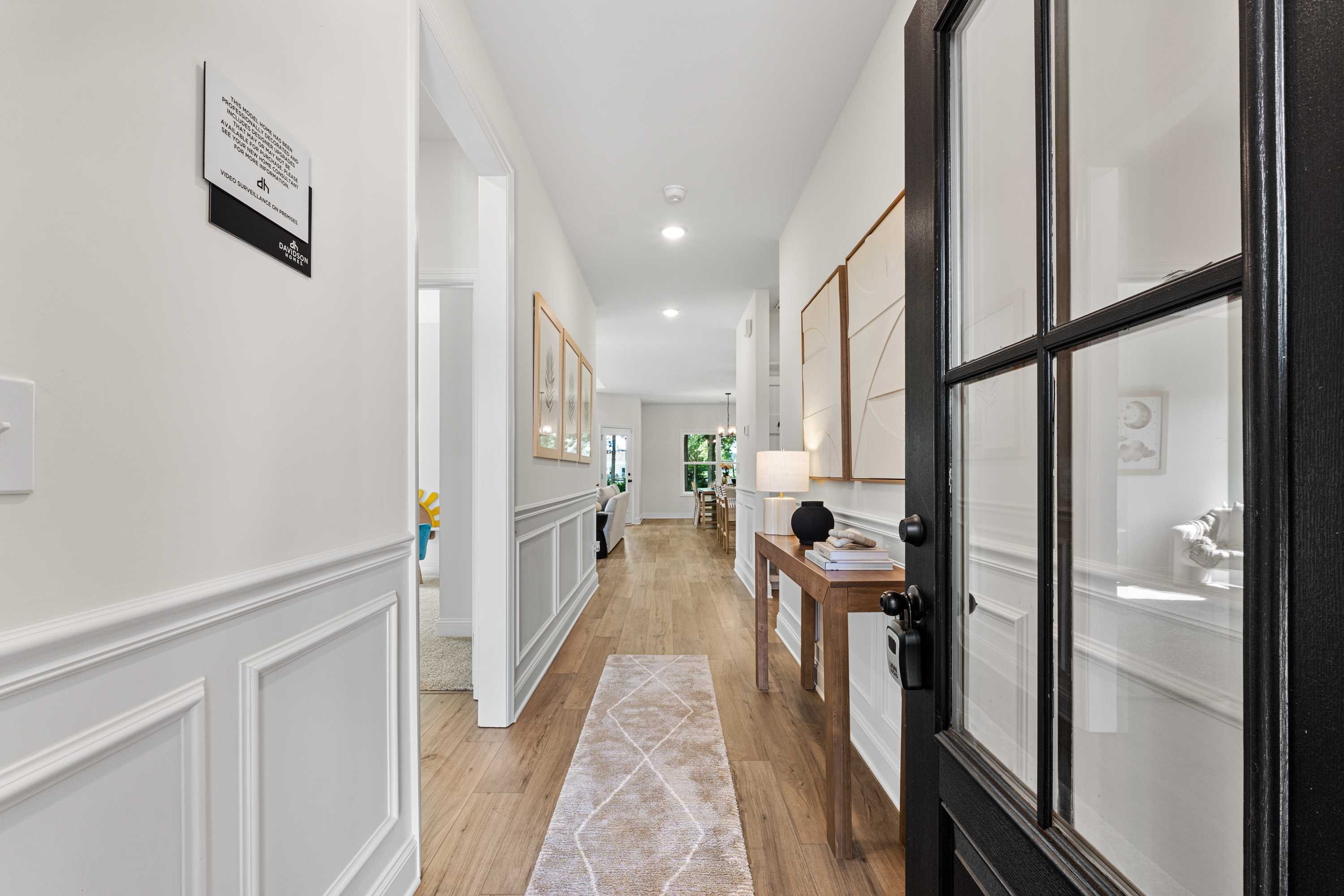Elegant foyer hallway at Lynn Meadows in Meridianville Alabama with wainscoting, hardwood floors, runner rug, and black glass door