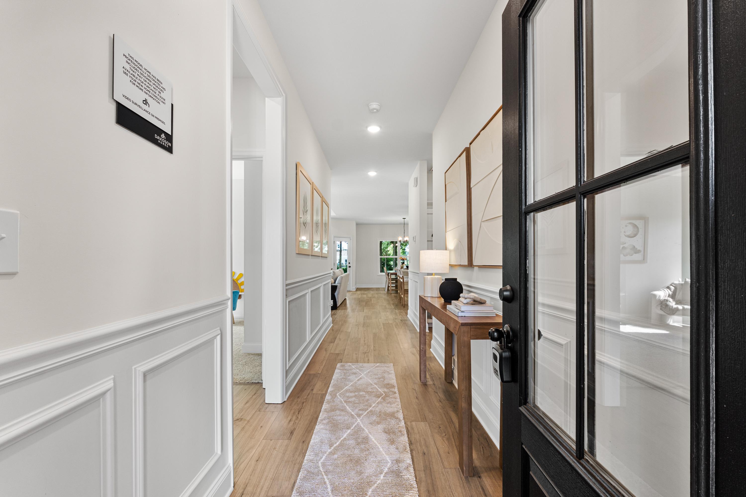 Elegant foyer hallway at Lynn Meadows in Meridianville Alabama with wainscoting, hardwood floors, runner rug, and black glass door