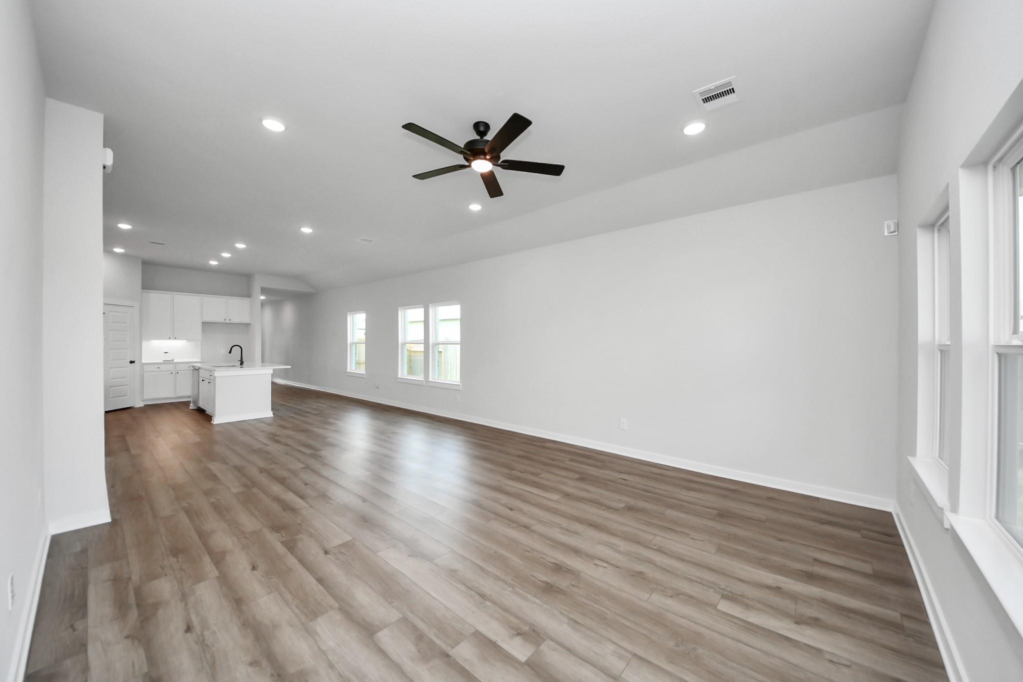 Spacious open-concept living area with wood-look flooring in The Riviera C floor plan at River Ranch Meadows, Dayton, Texas.