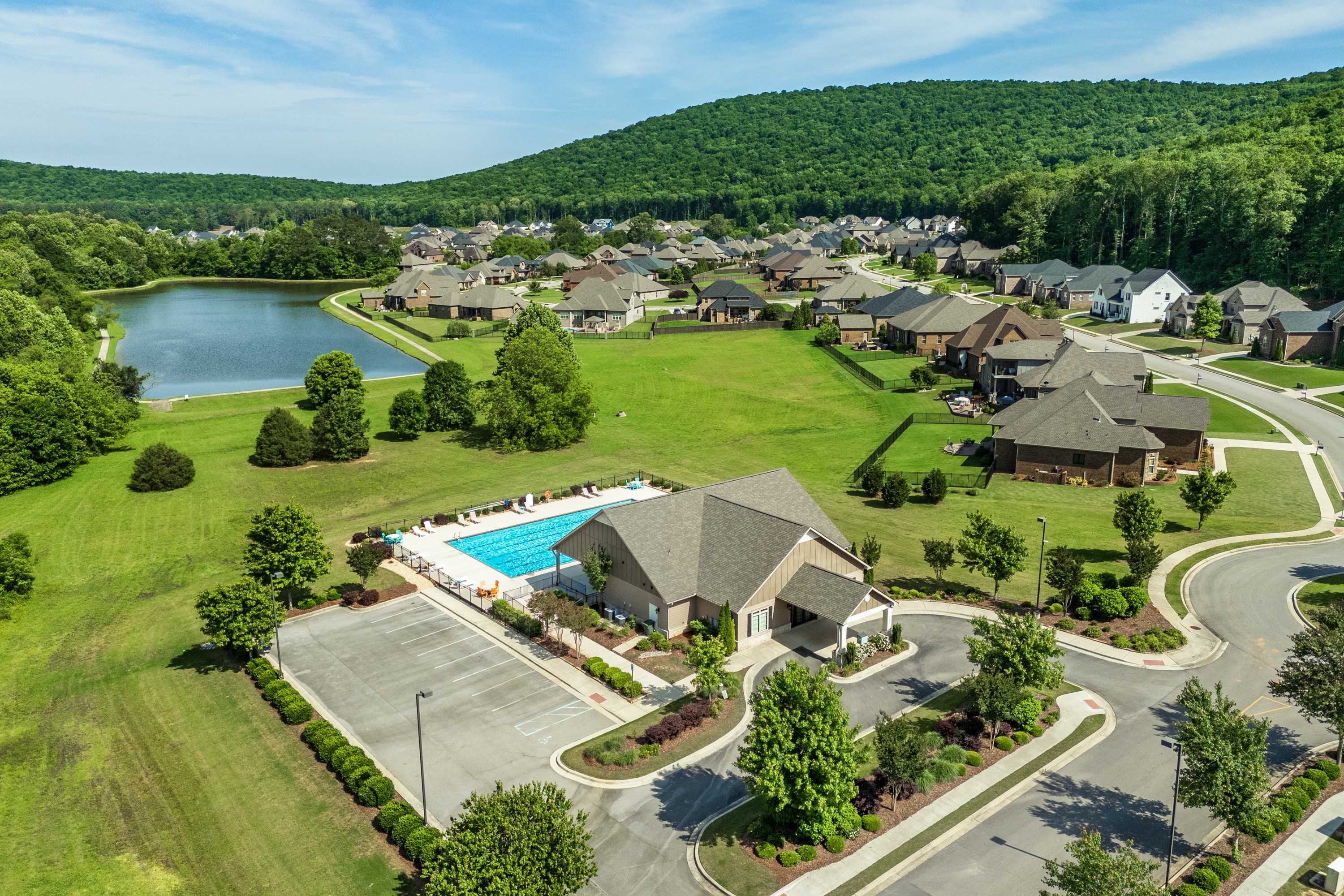 Aerial view of The Meadows at Hampton Cove in Owens Cross Roads Alabama featuring resort-style pool clubhouse pond and homes amid lush green hills