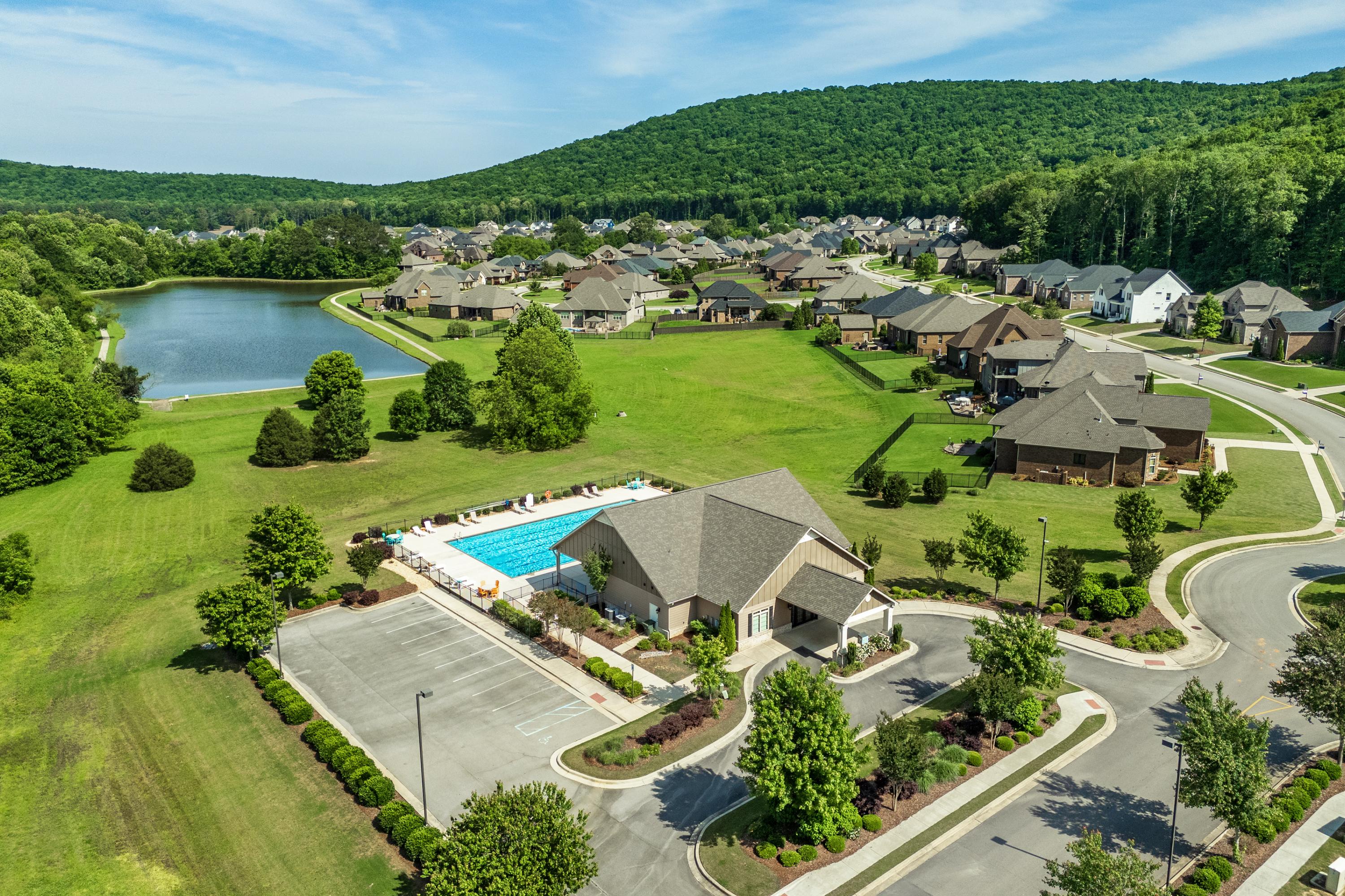 Aerial view of The Meadows at Hampton Cove in Owens Cross Roads Alabama featuring resort-style pool clubhouse pond and homes amid lush green hills