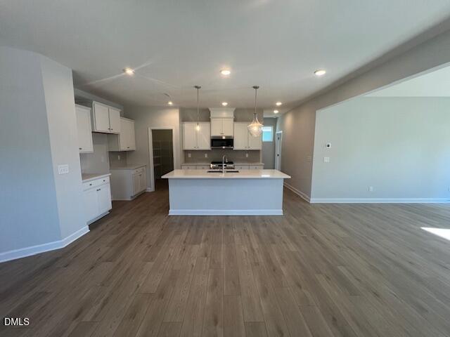 Modern open-concept kitchen with white island, stainless appliances, pendant lights, and hardwood floors in The Adalynn B, Lillington, NC