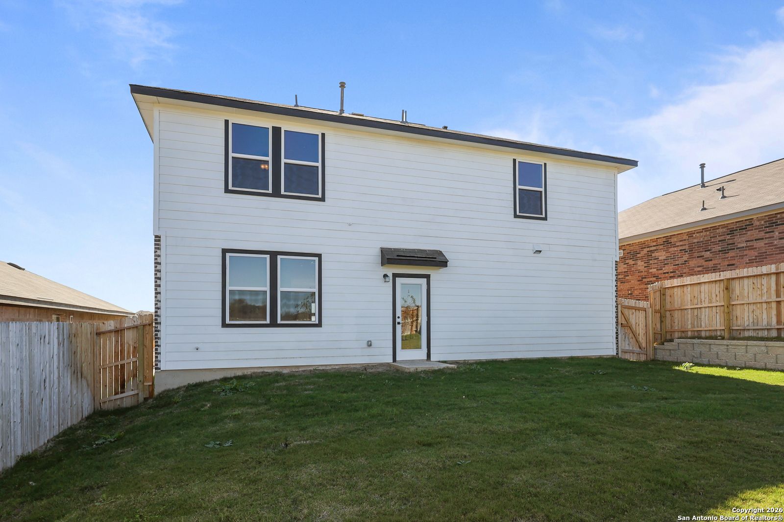 Two-story rear view of The Murray K home by Davidson Homes, covered patio, fenced green backyard in Comanche Ridge, San Antonio