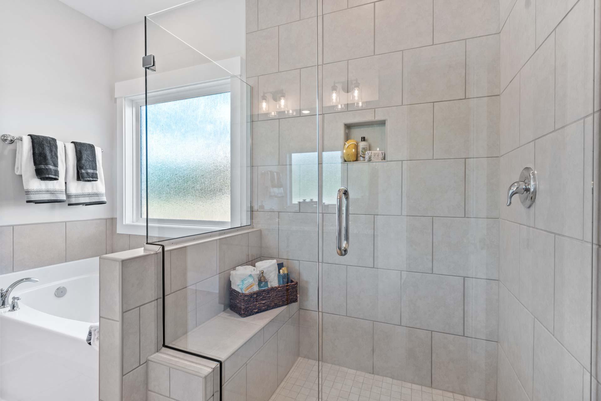 Spacious master bathroom in Blue Spring Huntsville AL with walk-in glass shower, freestanding tub, tiled walls, frosted window