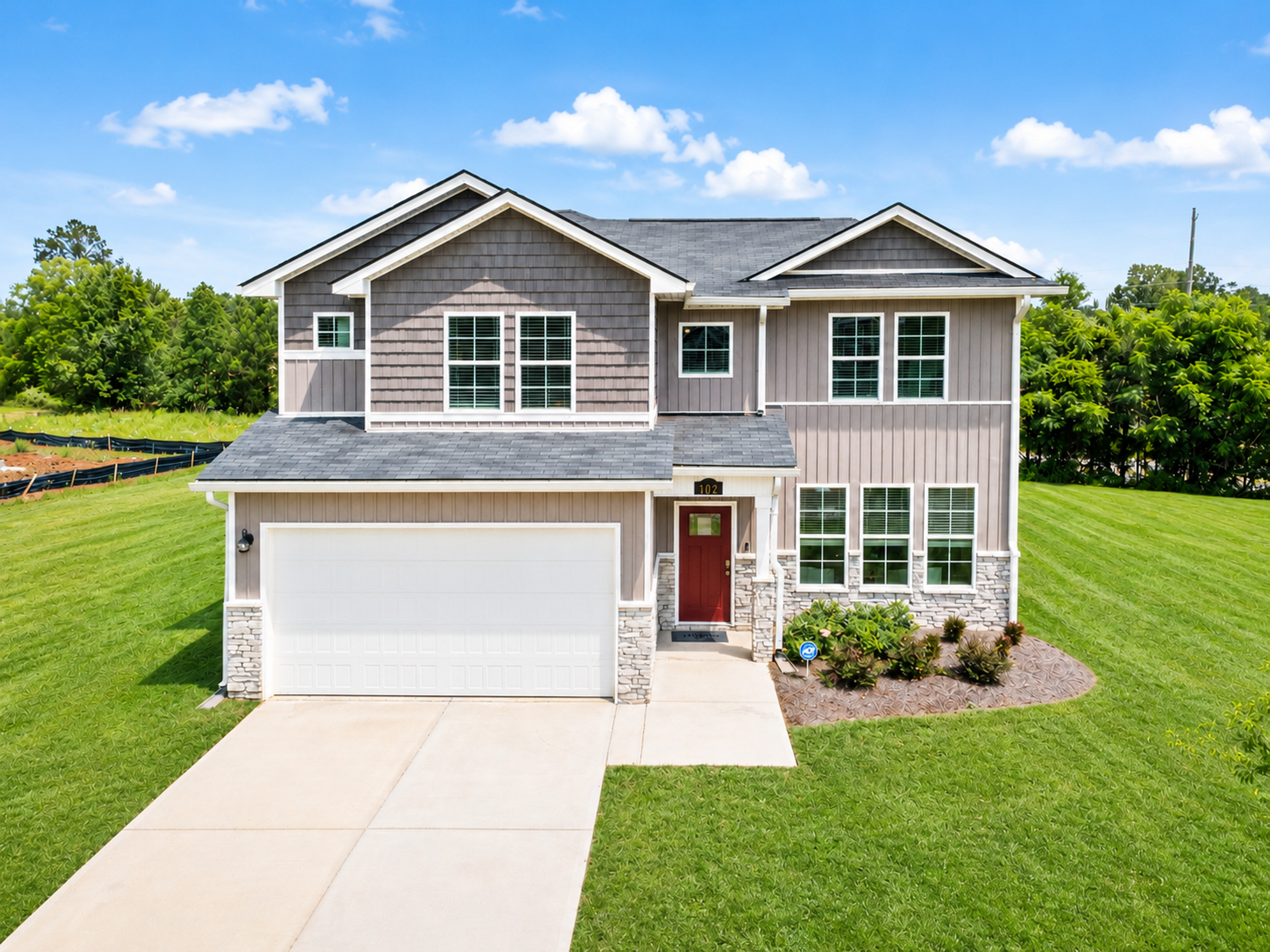 Two-story Davidson Homes exterior at Ivy Glen in Perry, Georgia, featuring gray siding, stone accents, and a red front door.