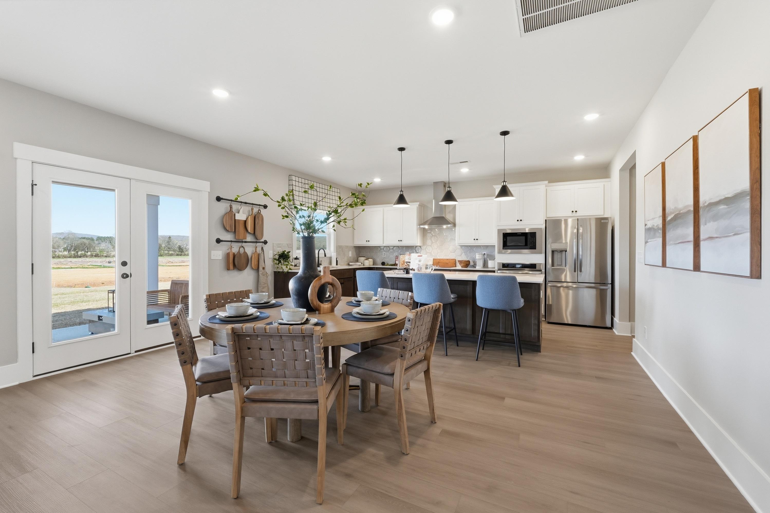 Spacious open-concept kitchen dining in Berry Cove New Market AL home with wood floors white cabinets stainless appliances French doors