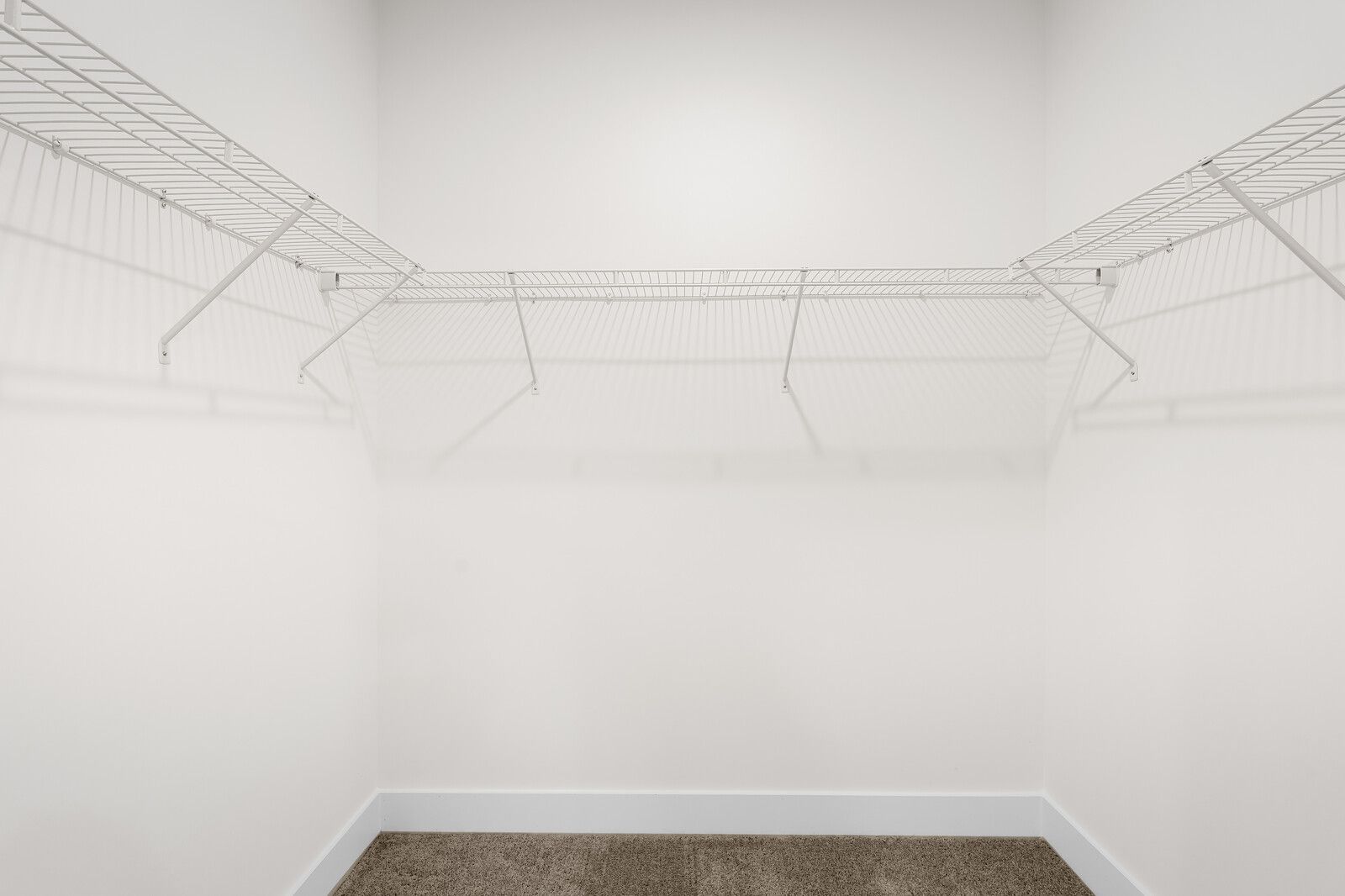 Spacious walk-in closet with white wire shelving in the master suite of The Cottonwood home design by Davidson Homes.