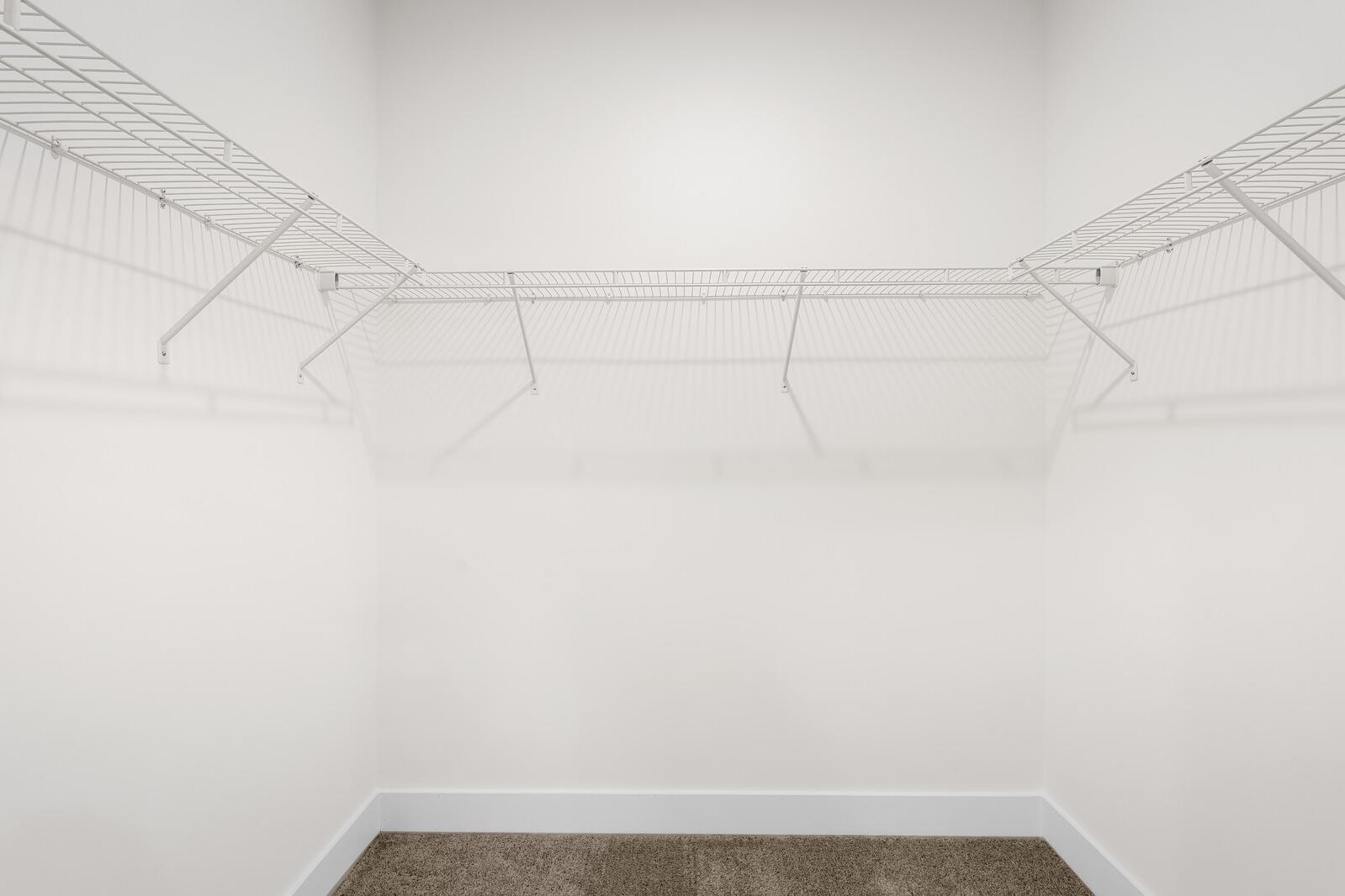 Spacious walk-in closet with white wire shelving in the master suite of The Cottonwood home design by Davidson Homes.