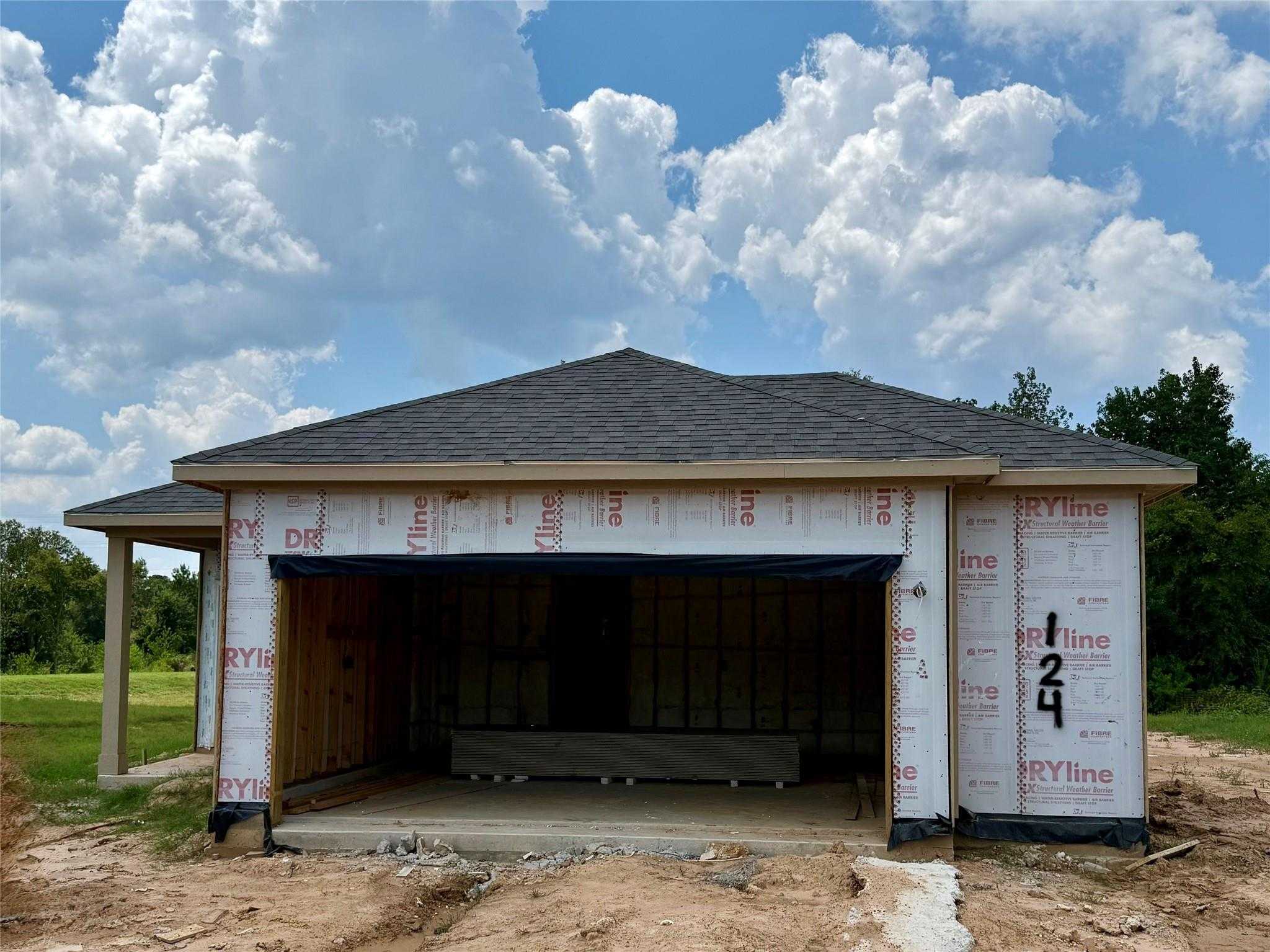 New construction single-story home with open 2-car garage and Tyvek exterior in Caney Creek Place, Conroe, Texas - Davidson Homes Colorado F