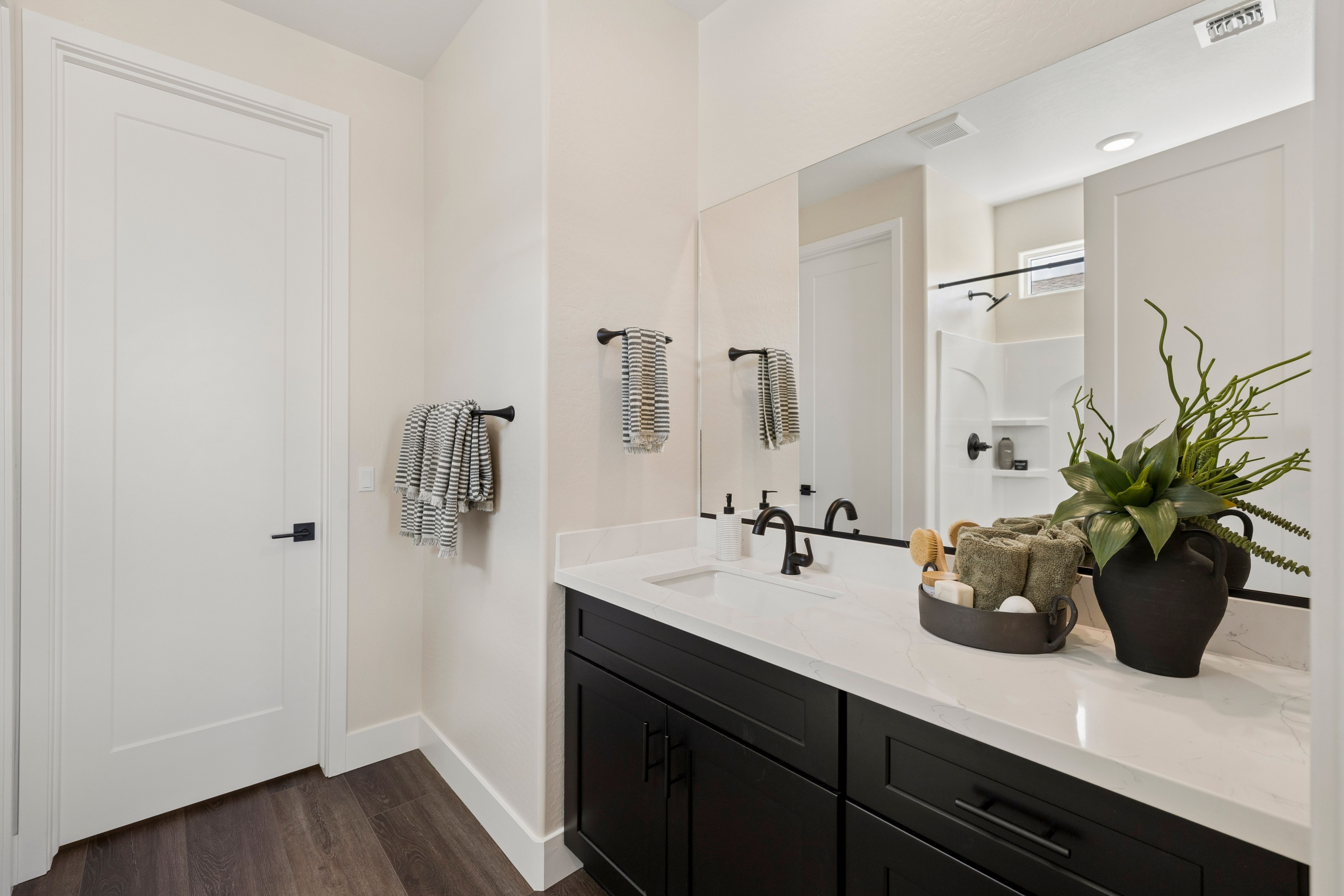 Modern bathroom vanity with black cabinets, white quartz countertop, and potted plants at South Ranch in Prescott AZ