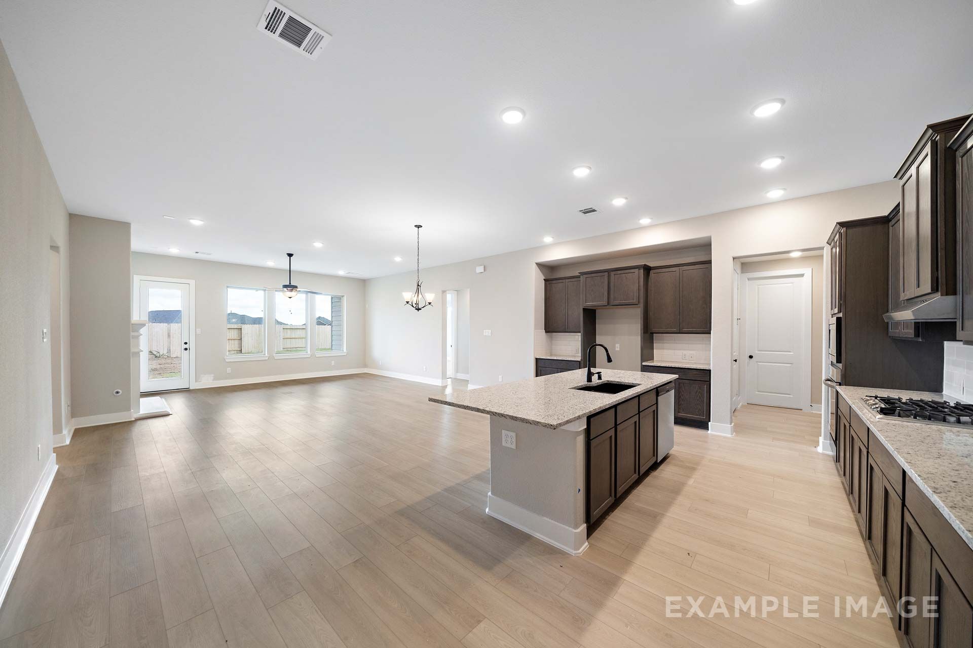 Open-concept kitchen and living area in The Elizabeth by Davidson Homes, featuring dark cabinets, granite island, and LVP flooring.