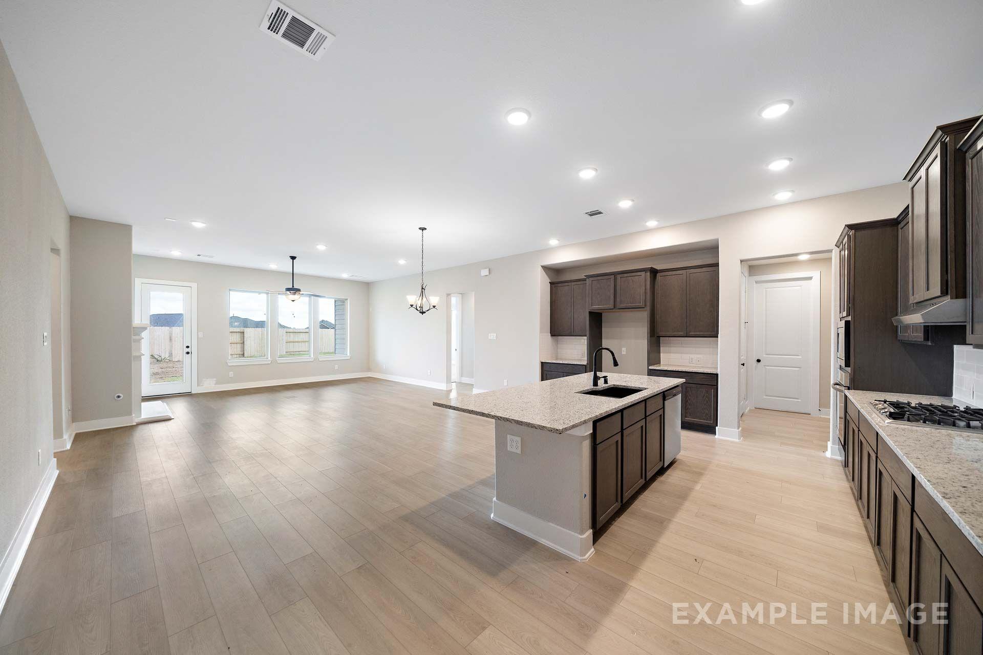 Open-concept kitchen and living area in The Elizabeth by Davidson Homes, featuring dark cabinets, granite island, and LVP flooring.