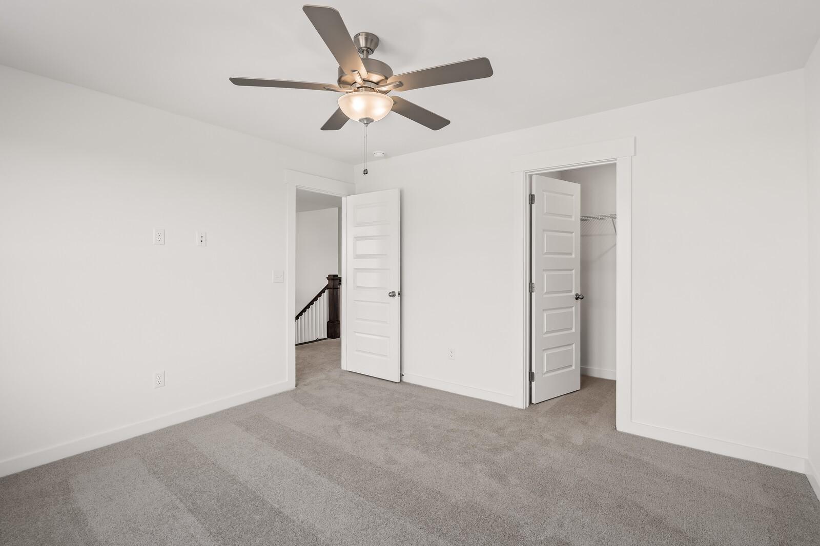 Spacious secondary bedroom with gray carpet, ceiling fan, double doors and staircase access in Davidson Homes The Willow D, Mt. Juliet