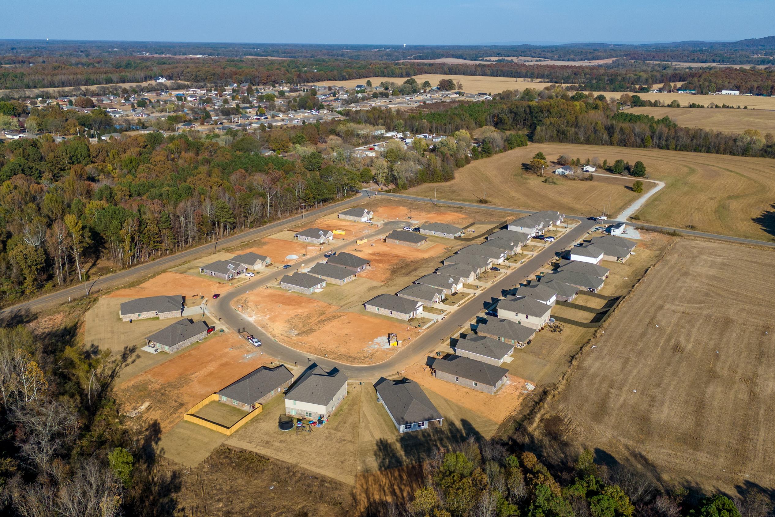 Aerial view of new homes under construction at Mallard Landing in Athens Alabama surrounded by autumn woods and fields