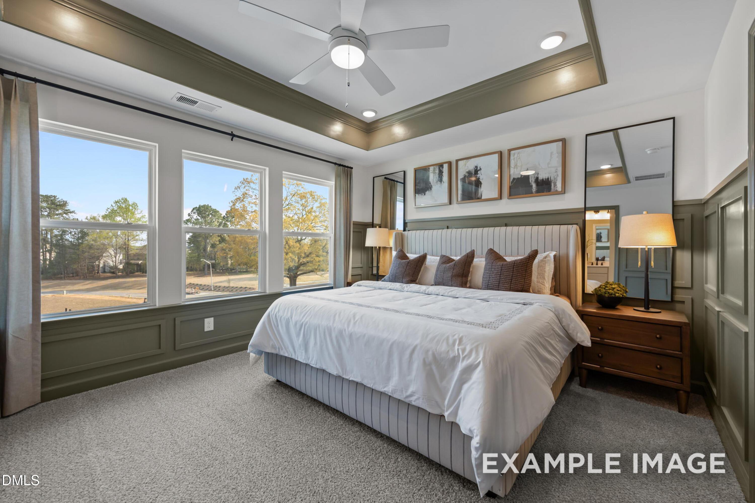 Elegant master bedroom with king bed, large windows overlooking wooded view, ceiling fan in Davidson Homes The Mitchell, Knightdale NC