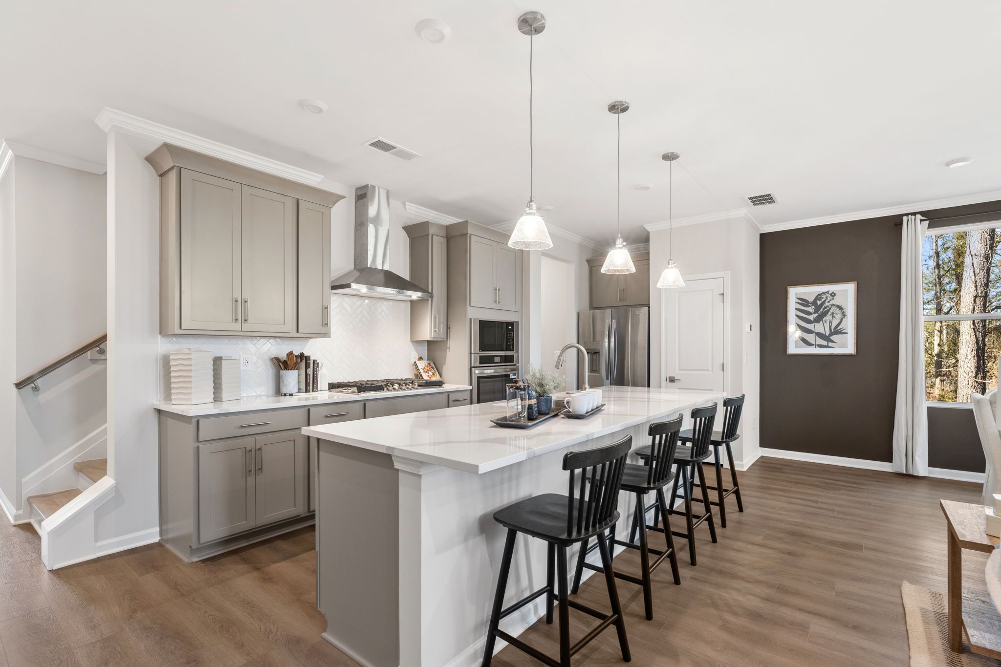 Modern open-concept kitchen at The Village at Shallowford in Kennesaw GA with white island, black stools, and hardwood floors