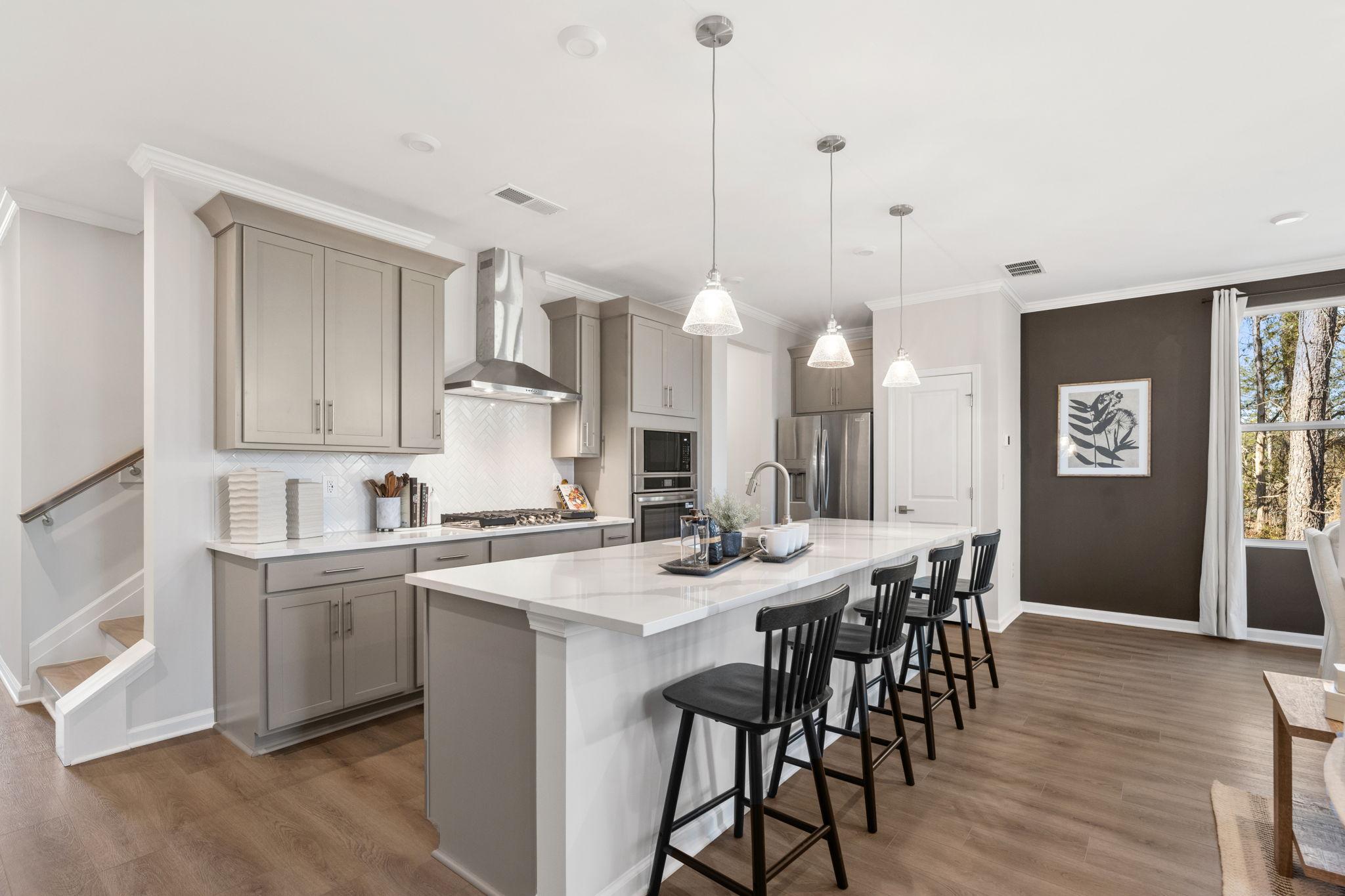 Modern open-concept kitchen at The Village at Shallowford in Kennesaw GA with white island, black stools, and hardwood floors