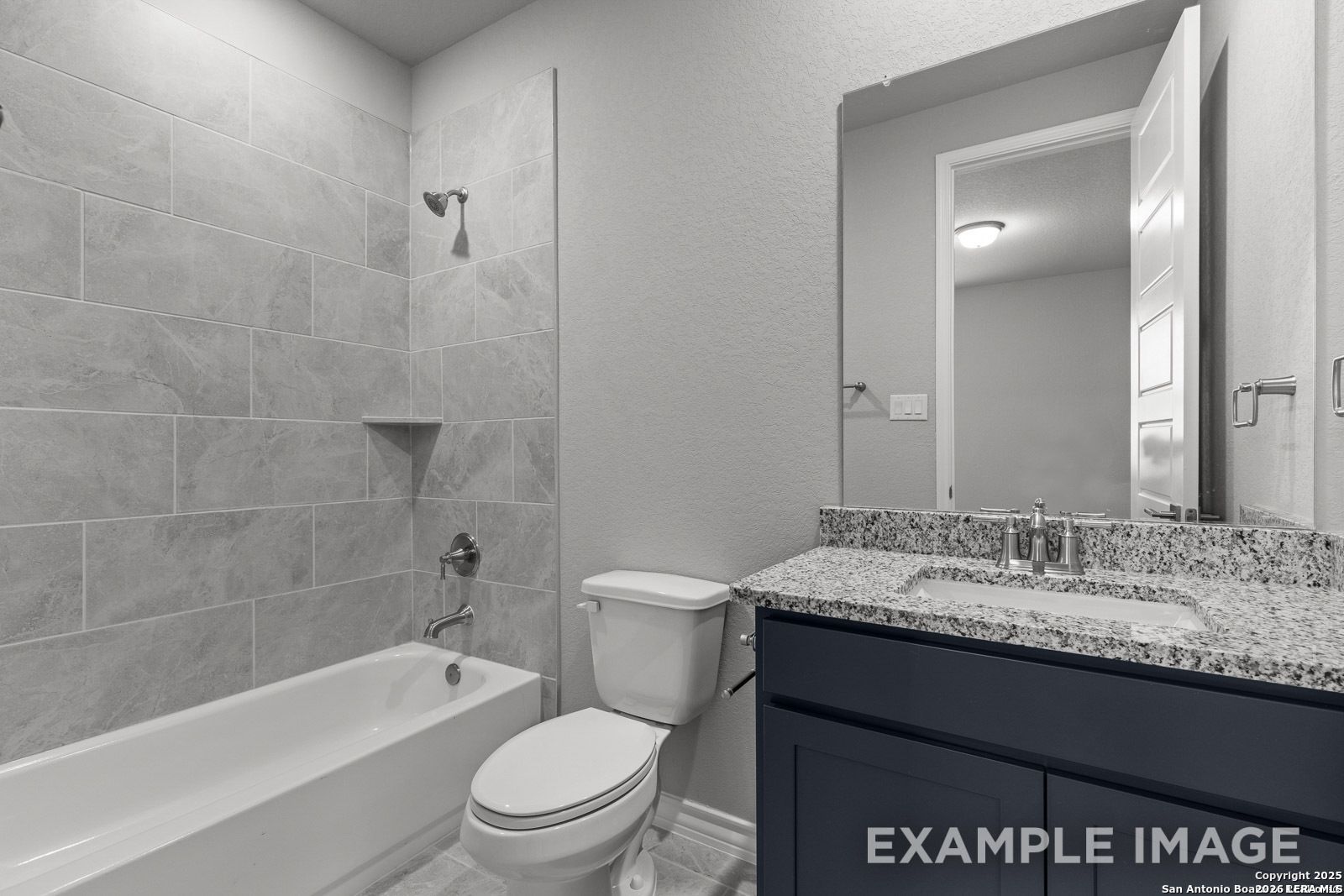 Modern bathroom with granite vanity and tiled tub-shower combo in Davidson Homes The Oxford F floor plan, Castroville, TX.