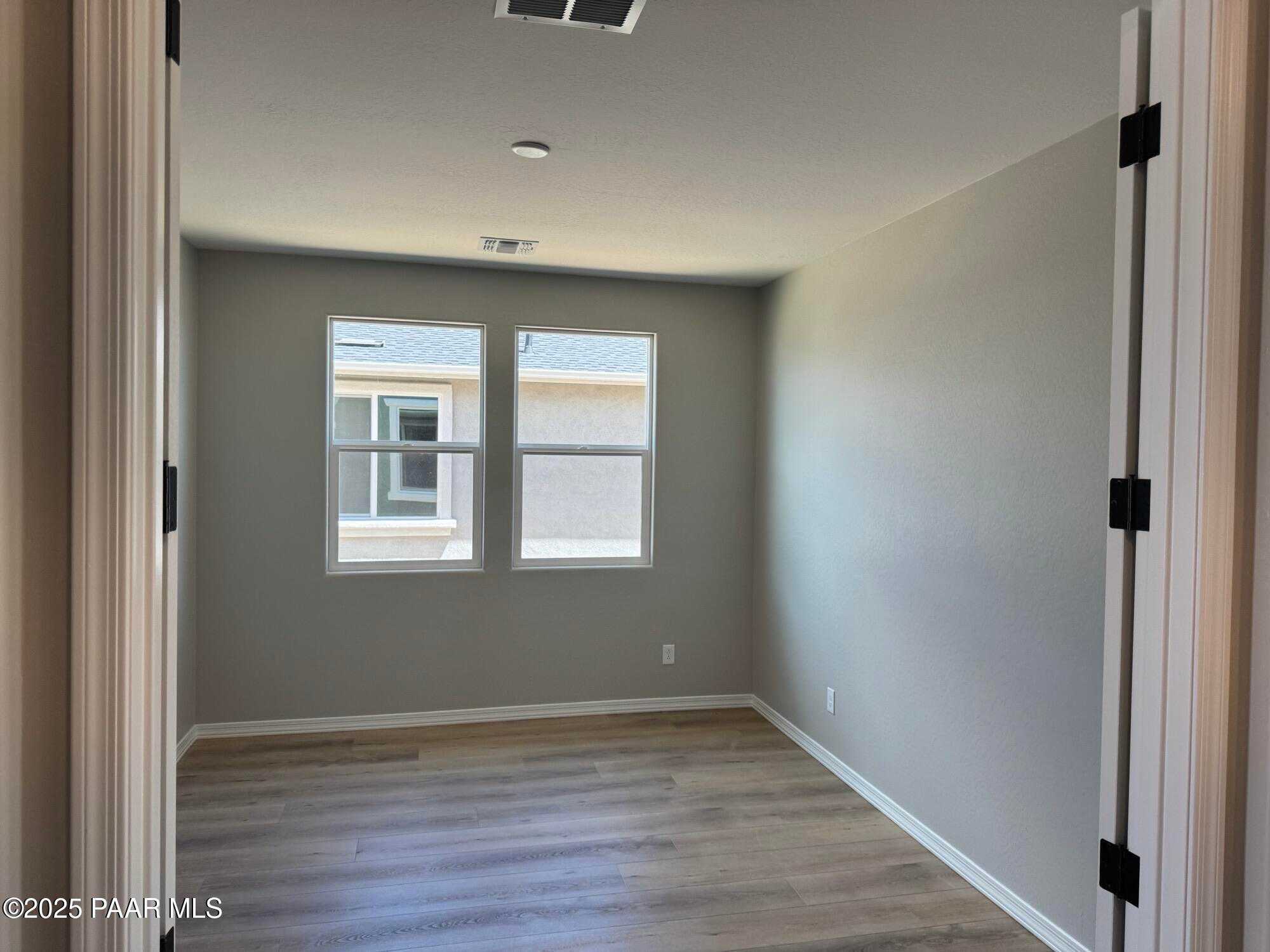 Bright secondary bedroom with dual windows, neutral gray walls, and hardwood floors in Davidson Homes The Sheridan II B, Prescott, AZ