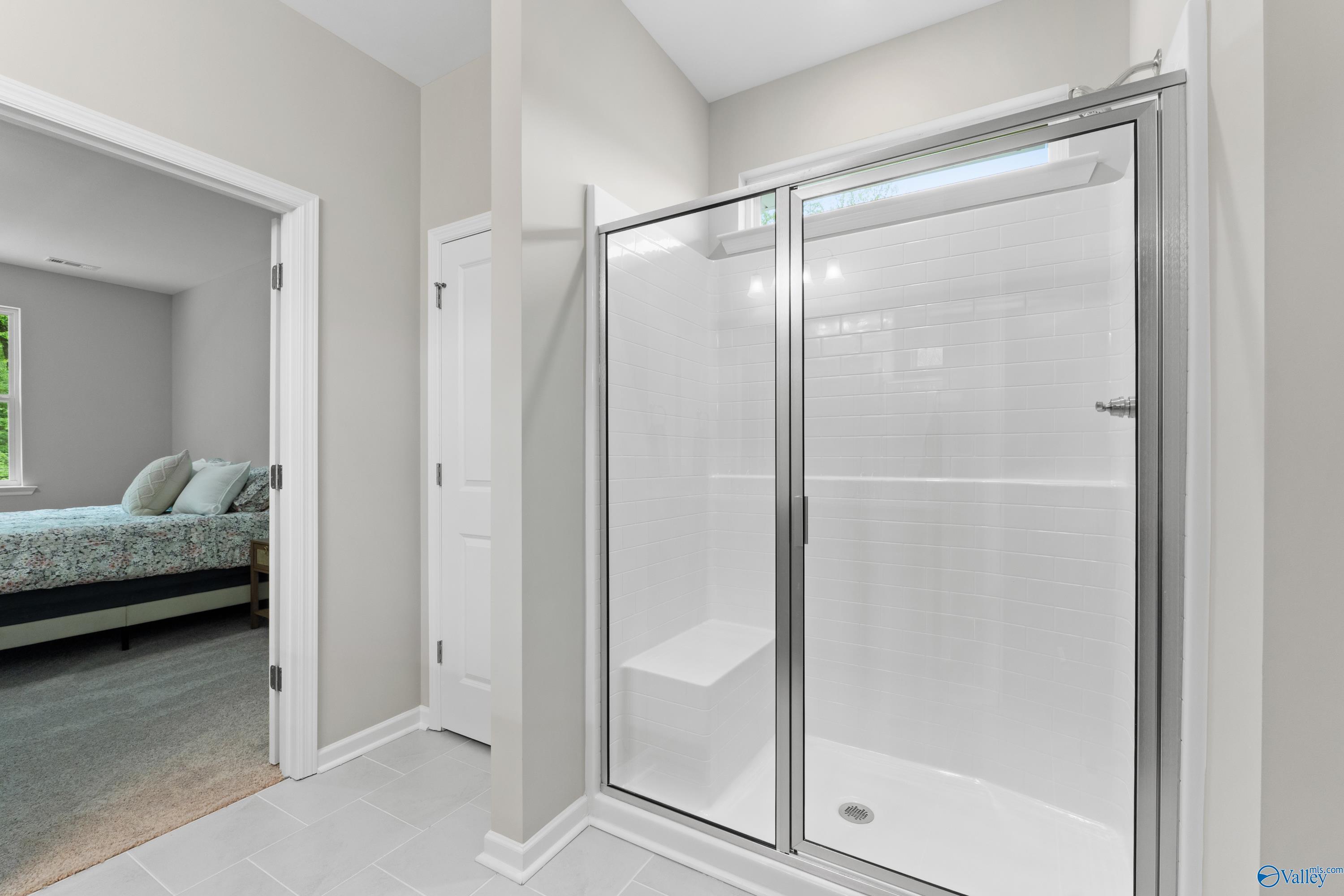 Modern master bath with frameless glass shower, white tile, and bench in Davidson Homes The Luna, Hazel Green, AL