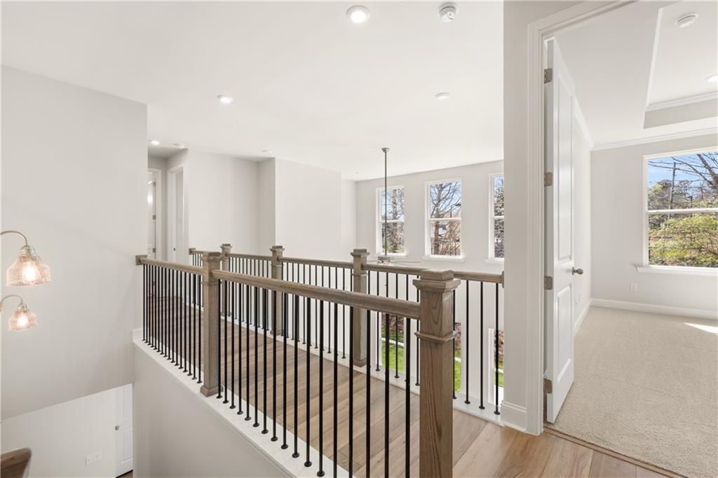 Elegant wood-and-iron balcony railing overlooking open two-story interior with large windows in The Danbury C, Buford, GA