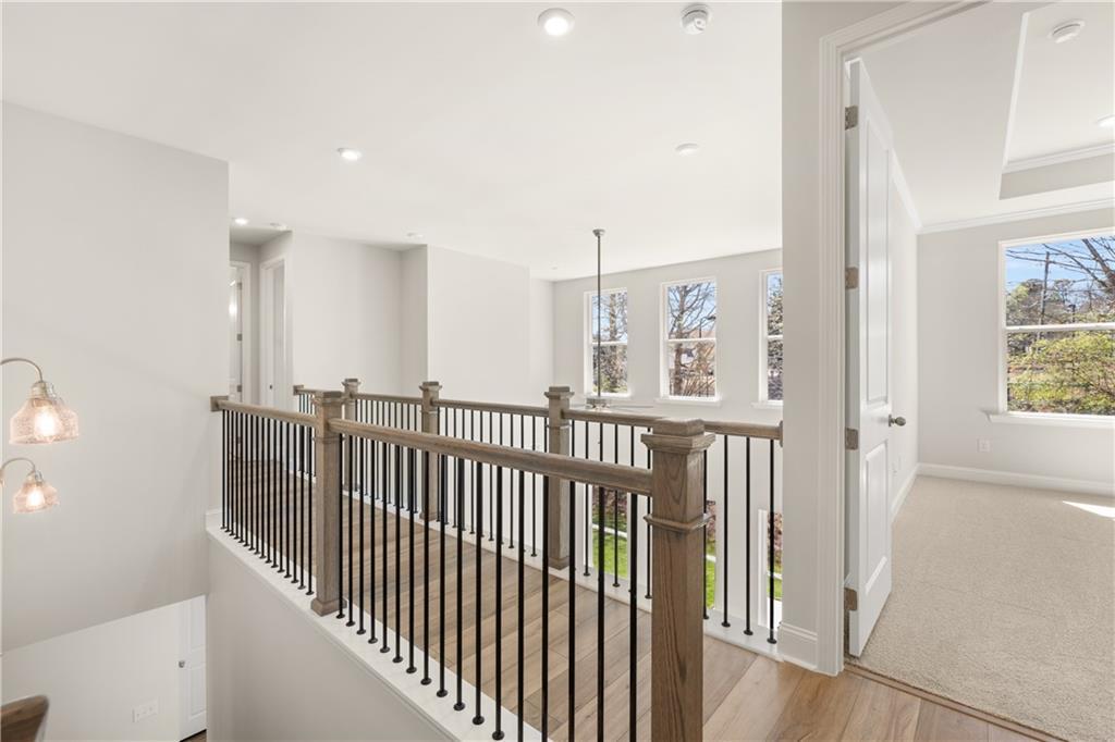 Elegant wood-and-iron balcony railing overlooking open two-story interior with large windows in The Danbury C, Buford, GA