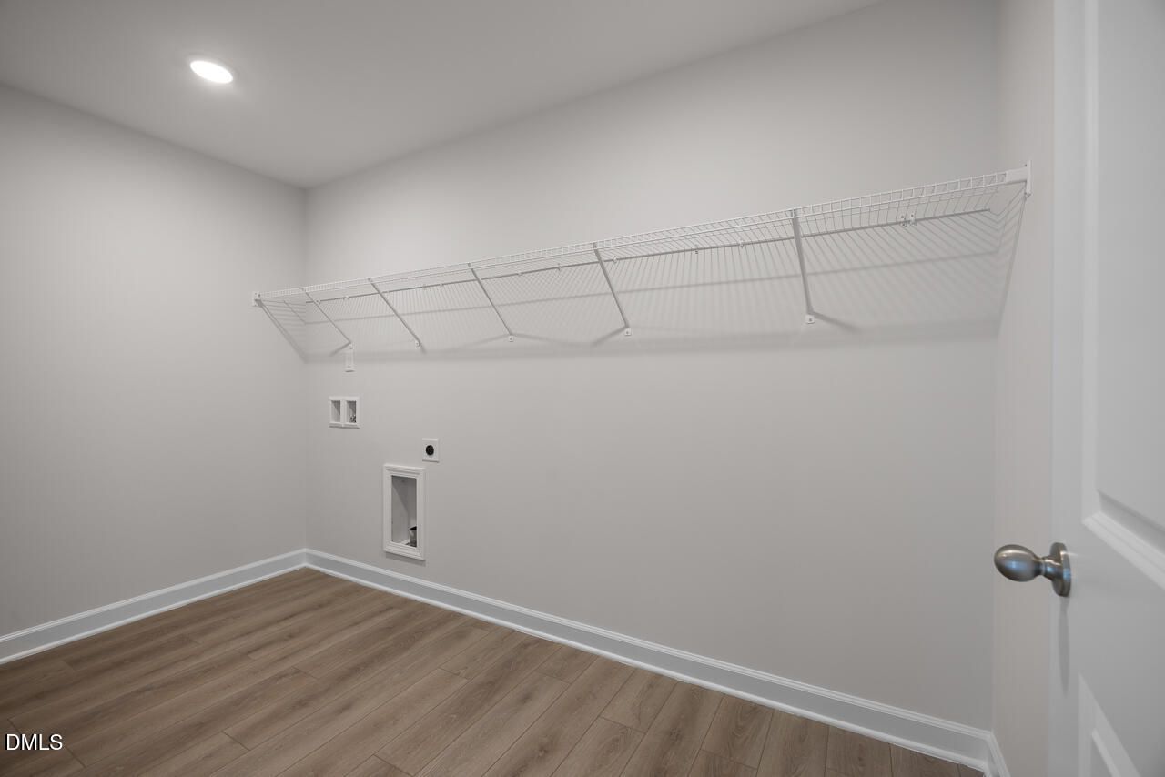 Laundry room with wire shelving and utility hookups in The Hickory II B floor plan at Wellers Knoll, Lillington, NC.