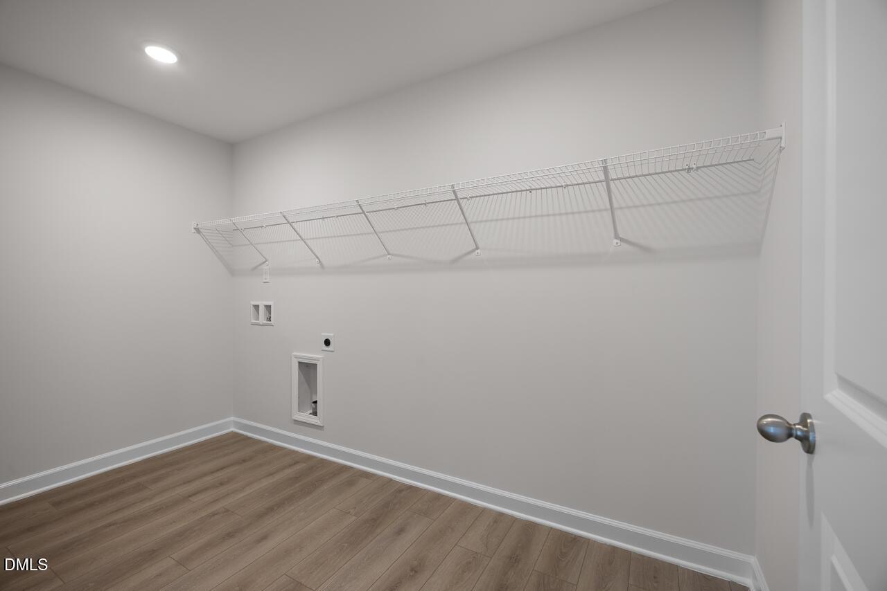 Laundry room with wire shelving and utility hookups in The Hickory II B floor plan at Wellers Knoll, Lillington, NC.