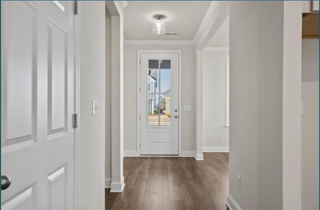 Bright entryway with white door and wood-style flooring in The Ash C floor plan at Wehunt Meadows, Hoschton, Georgia.