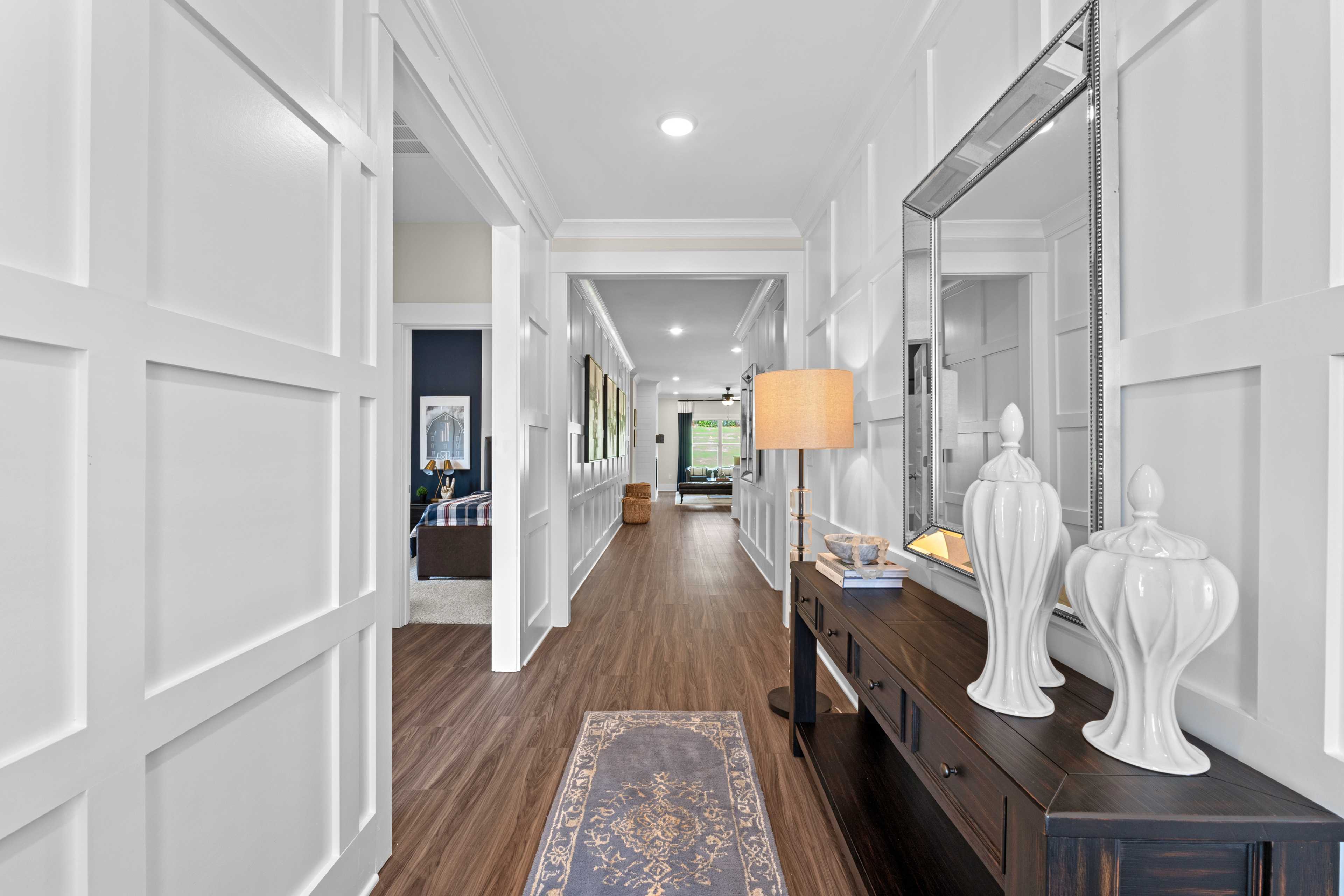 Spacious hallway interior at Ivy Hills in Toney Alabama with white paneled walls, hardwood floors and console table