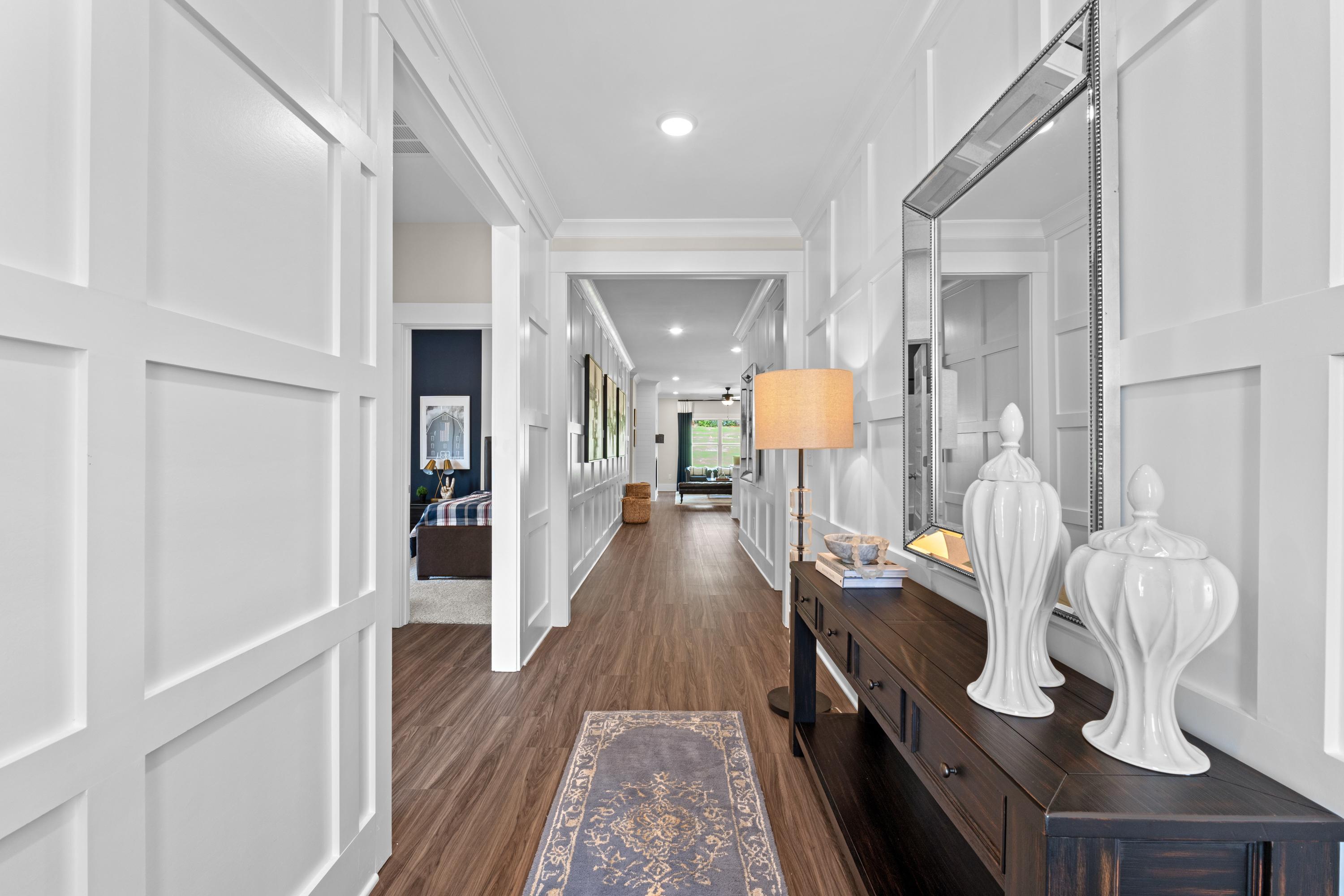 Spacious hallway interior at Ivy Hills in Toney Alabama with white paneled walls, hardwood floors and console table